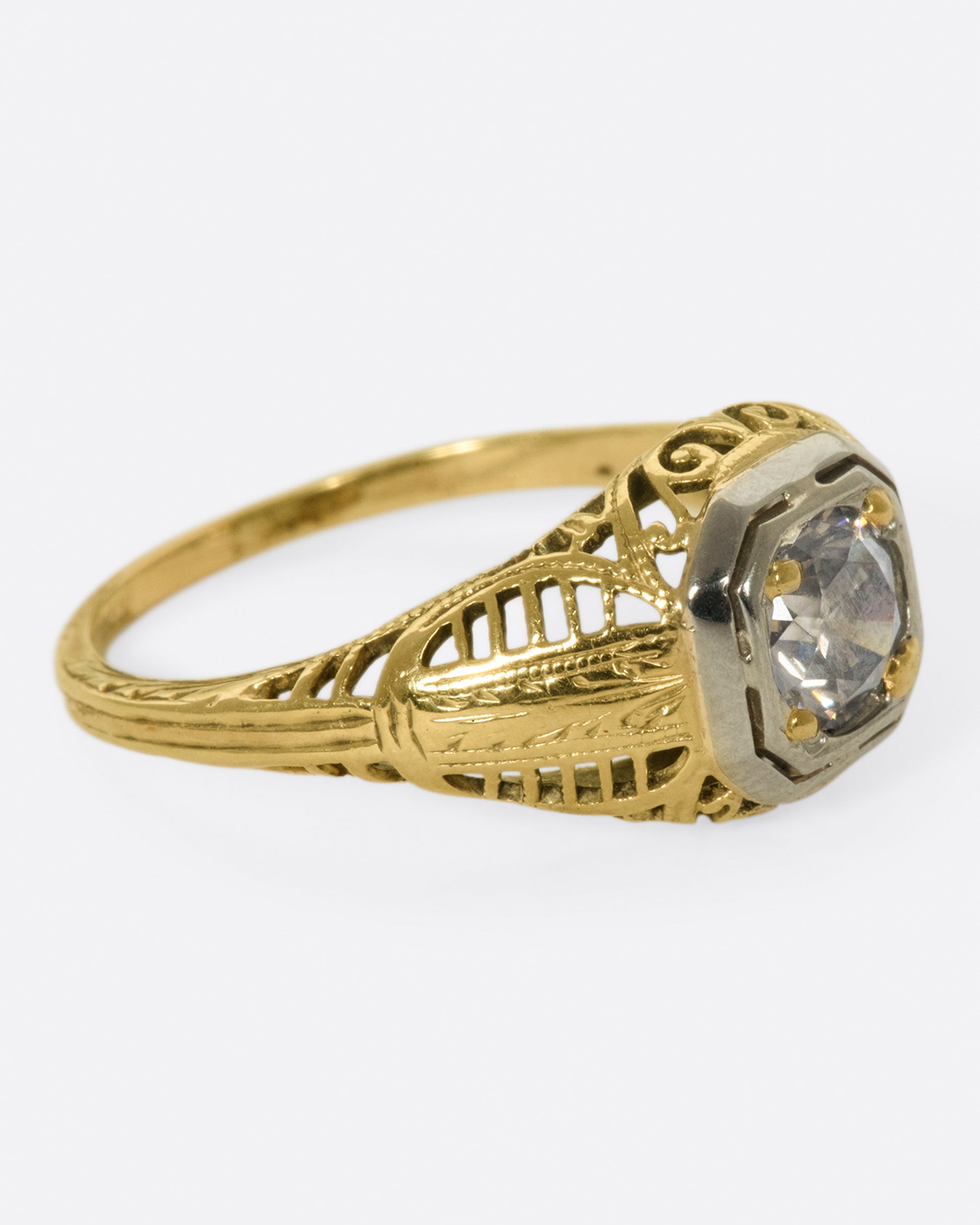 A filigree-covered signet ring with a champagne diamond at its center, set in a white gold bezel.