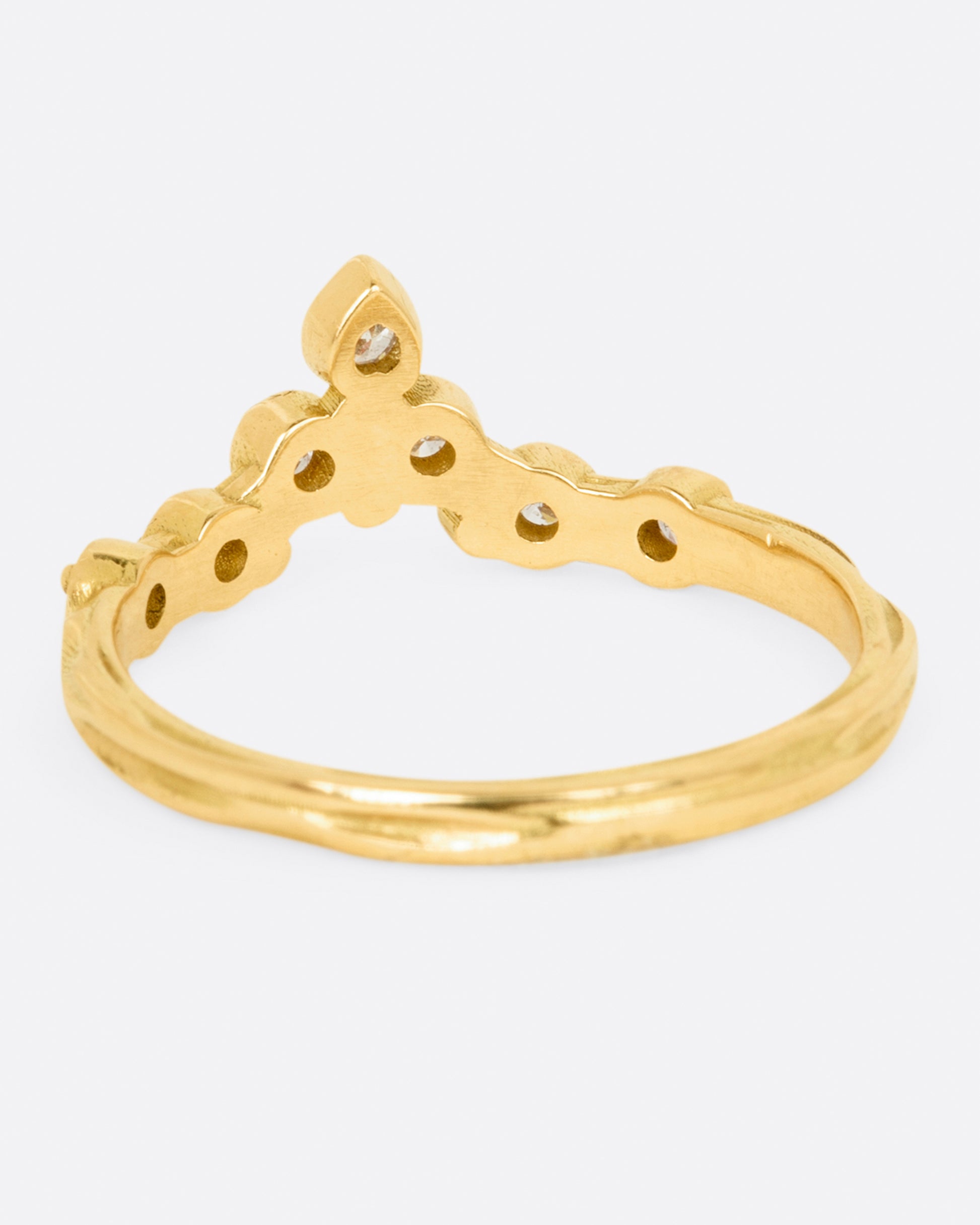 A slightly curved and pointed ring with seven diamonds on a textured band.
