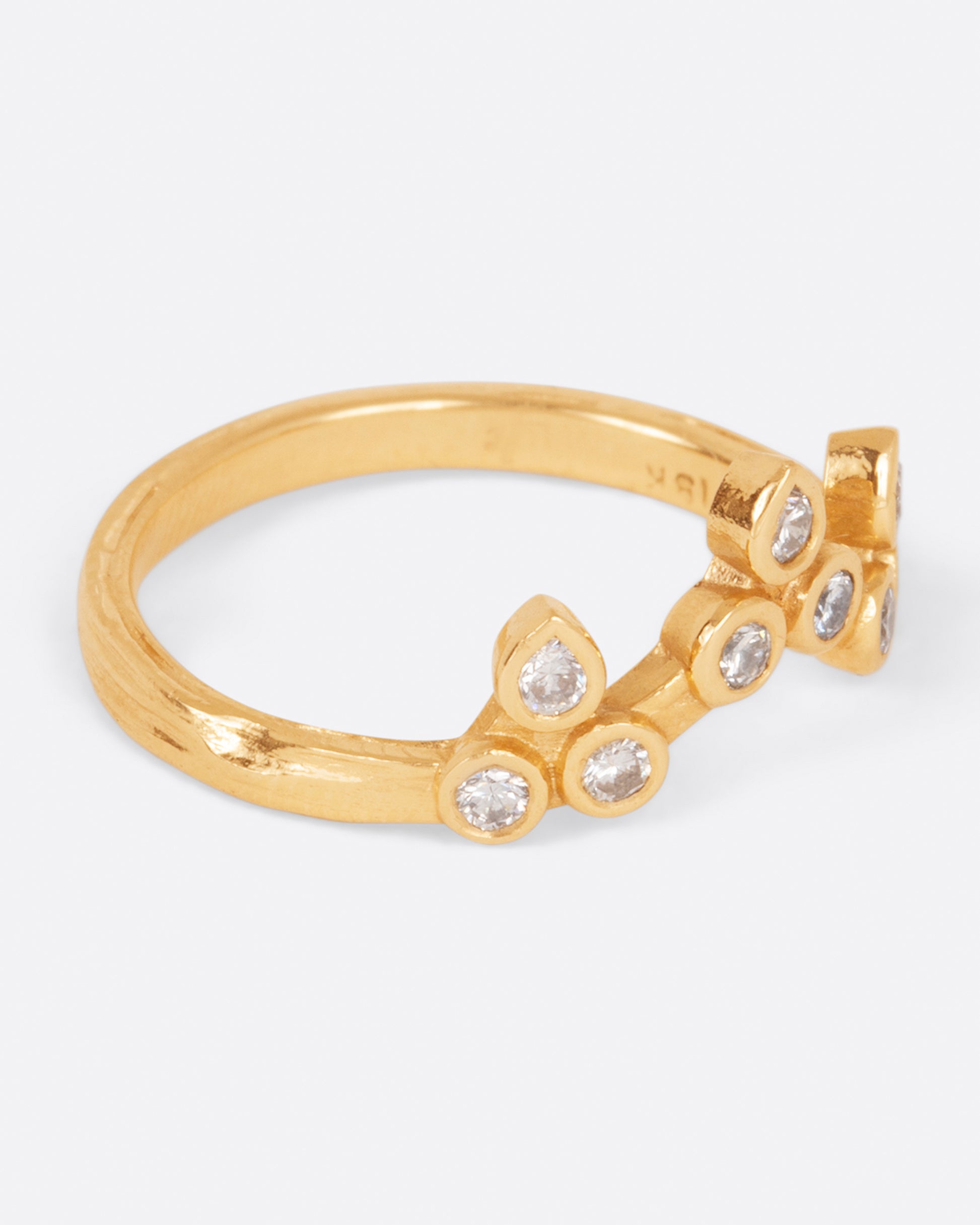 A curved yellow gold ring with a crown of round white diamonds, shown from the side.