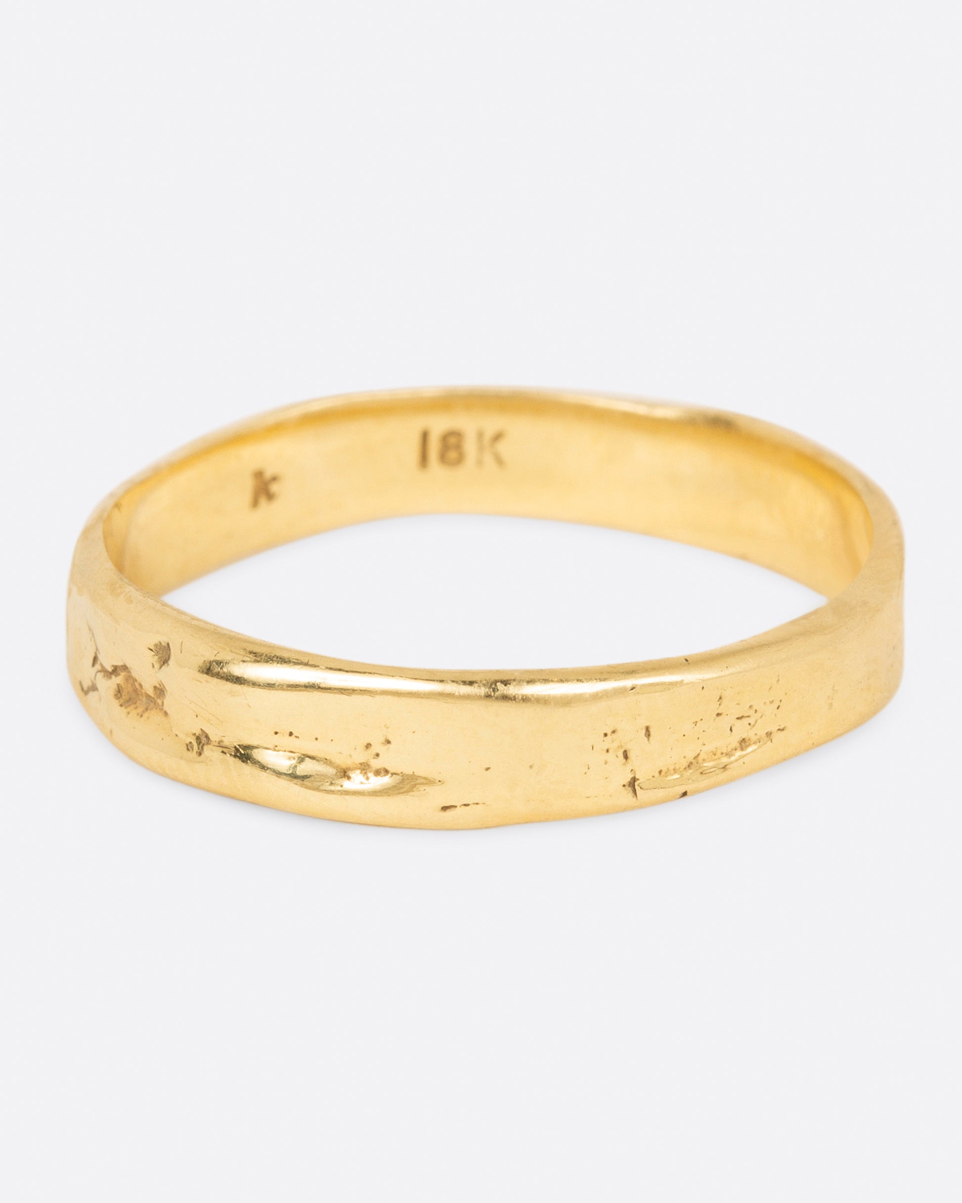 A textured yellow gold band that is meant to look worn in, shown from the front.