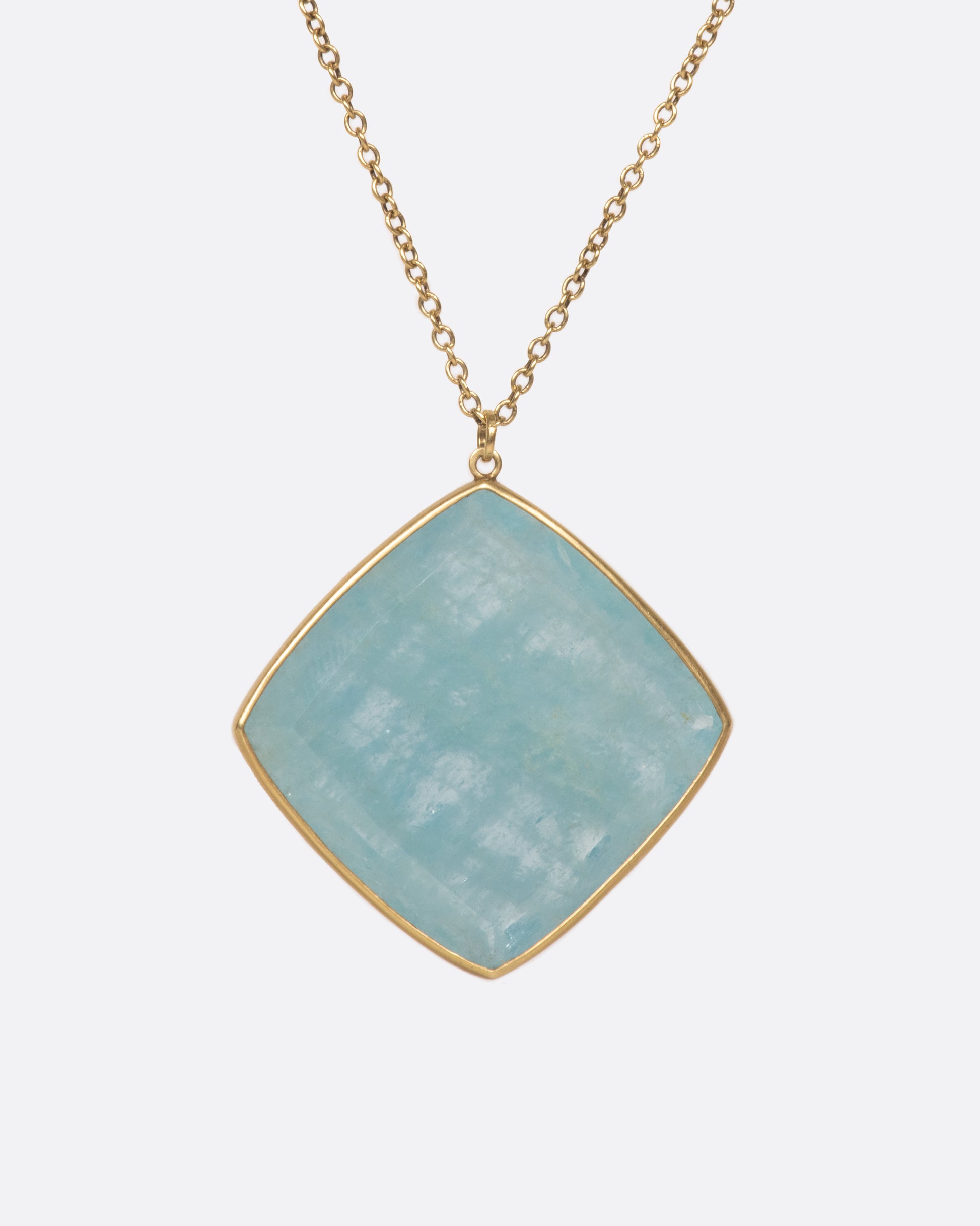 A large square aquamarine pendant hangings on a green gold chain, shown from the front.