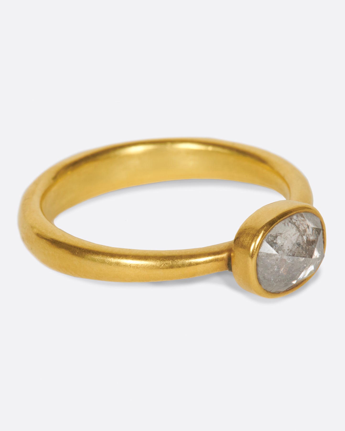 A pale grey, rose cut, oval diamond. Set horizontally on a simple, solid gold band, for a comfortably luxurious and unique design.