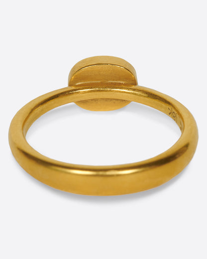 A pale grey, rose cut, oval diamond. Set horizontally on a simple, yellow gold band. Shown from the back.
