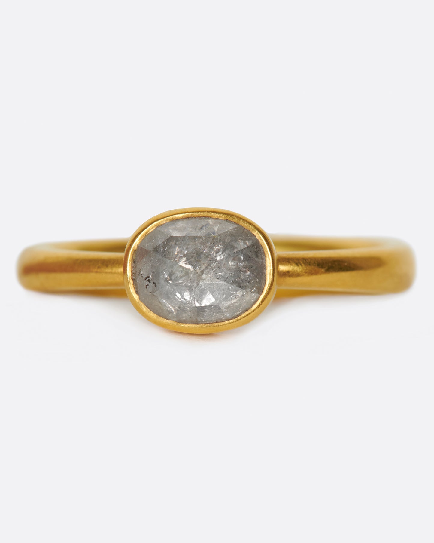 A pale grey, rose cut, oval diamond. Set horizontally on a simple, solid gold band, for a comfortably luxurious and unique design.