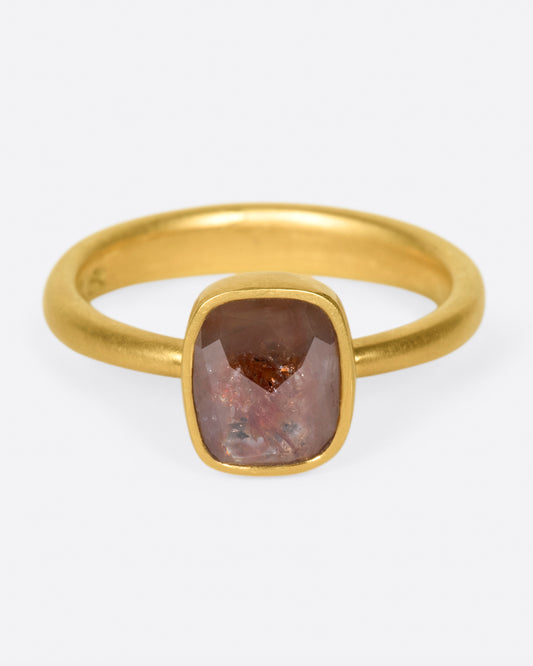 A cushion shaped, rusty-red diamond in one of Lola Brooks' signature bezel settings.