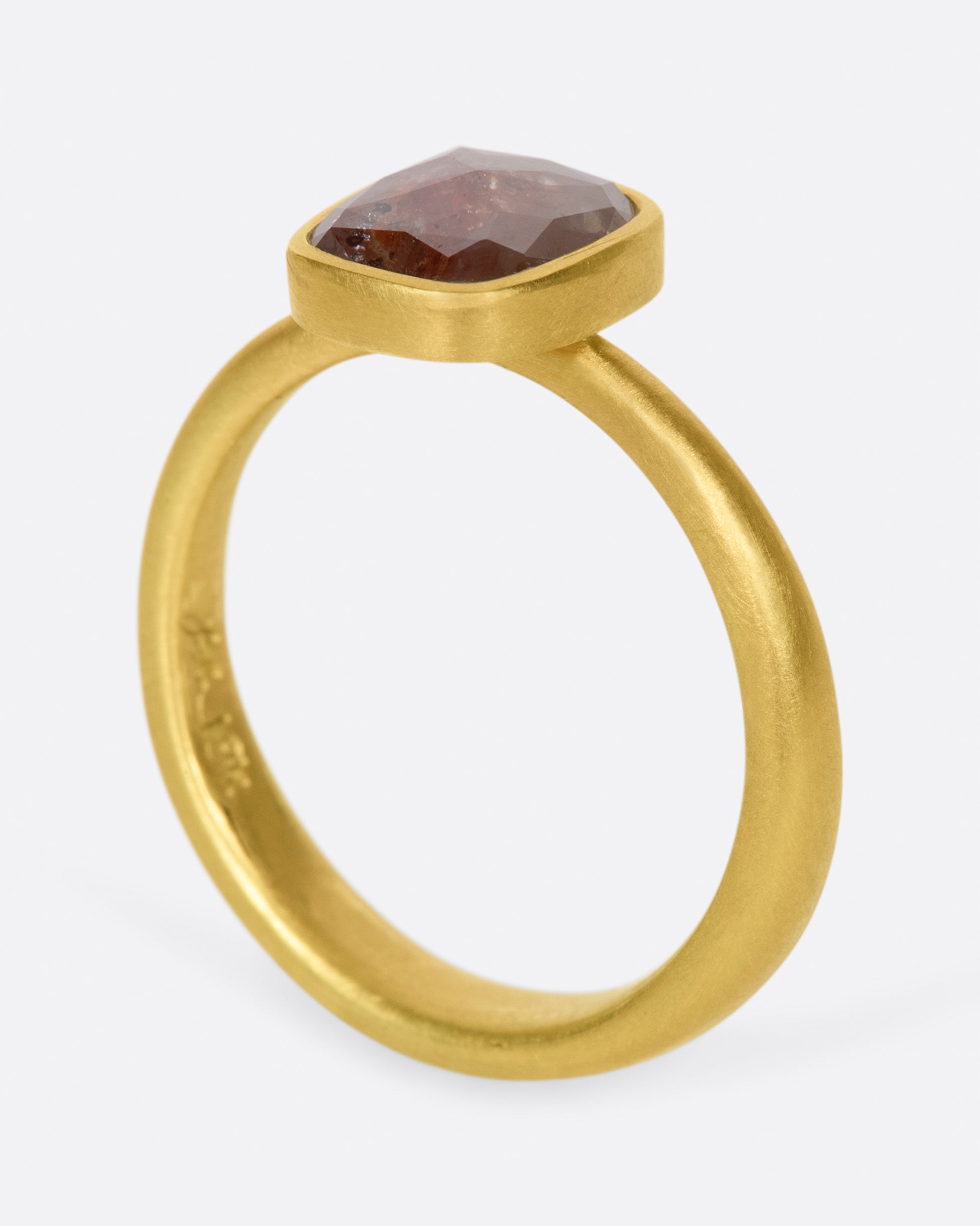 A cushion shaped, rusty-red diamond in one of Lola Brooks' signature bezel settings.