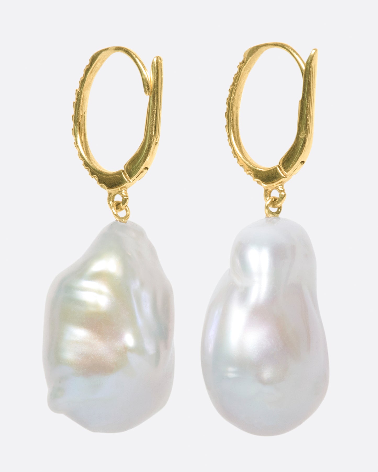 two dangle drop earrings hanging and viewed from the back. the drop is a pearl that has been partially carved out and lined with amethysts. the yellow gold hooks have pave diamonds on the bail.