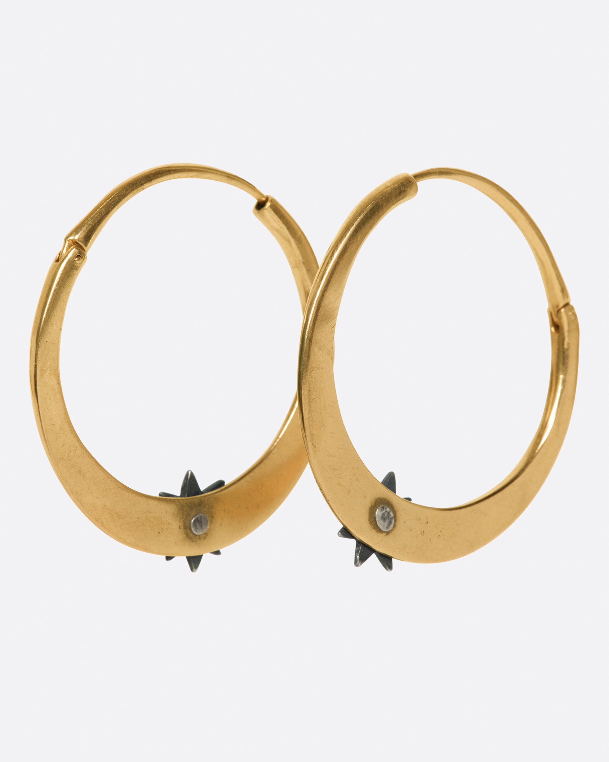A pair of rose gold tapered hoop earrings with sterling silver stars at their base, shown from the back.