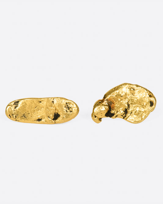 A pair of mismatched gold nugget stud earrings, shown laying flat.