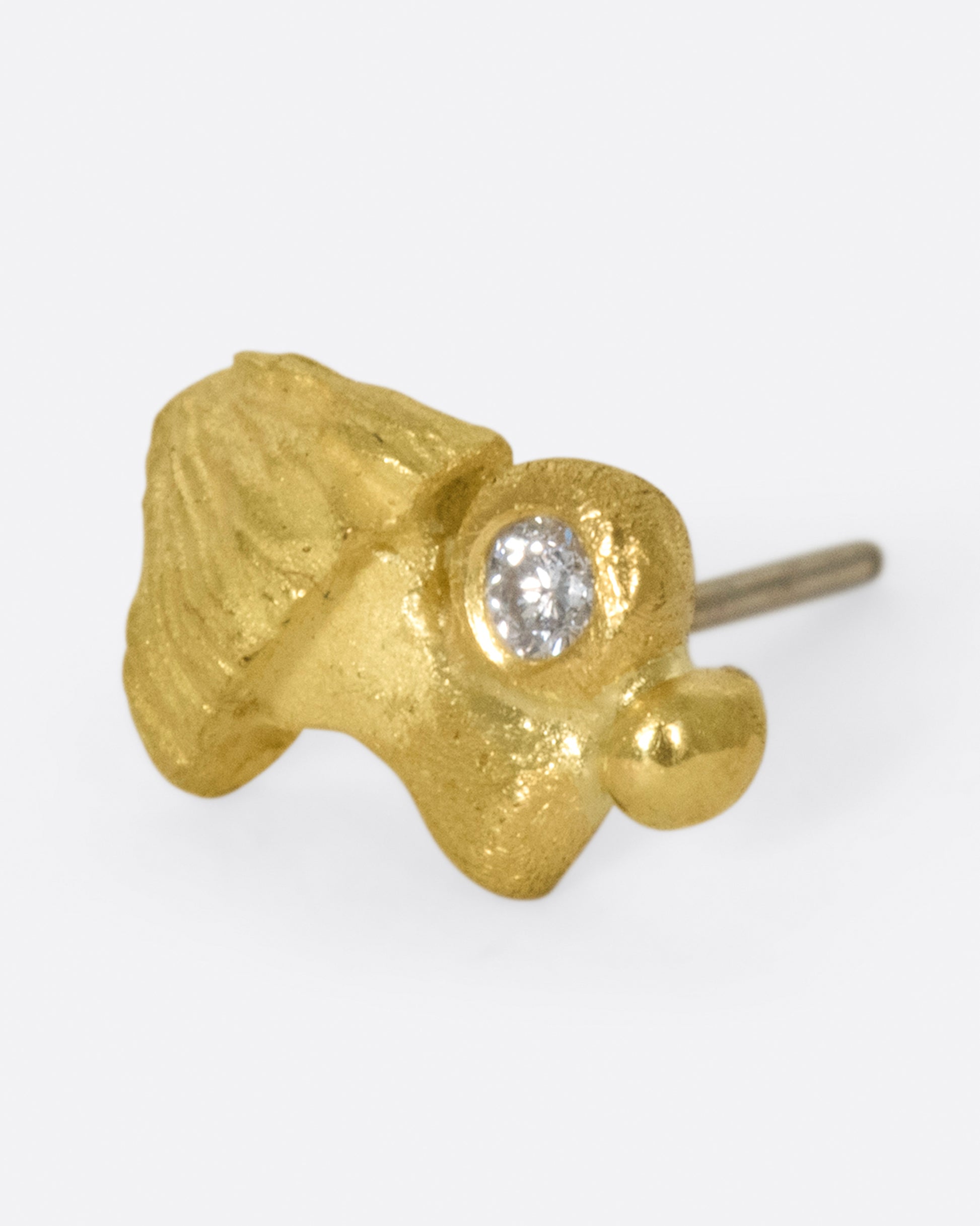 Matte gold and hand carved, this little fungus remains subtle on the ear.