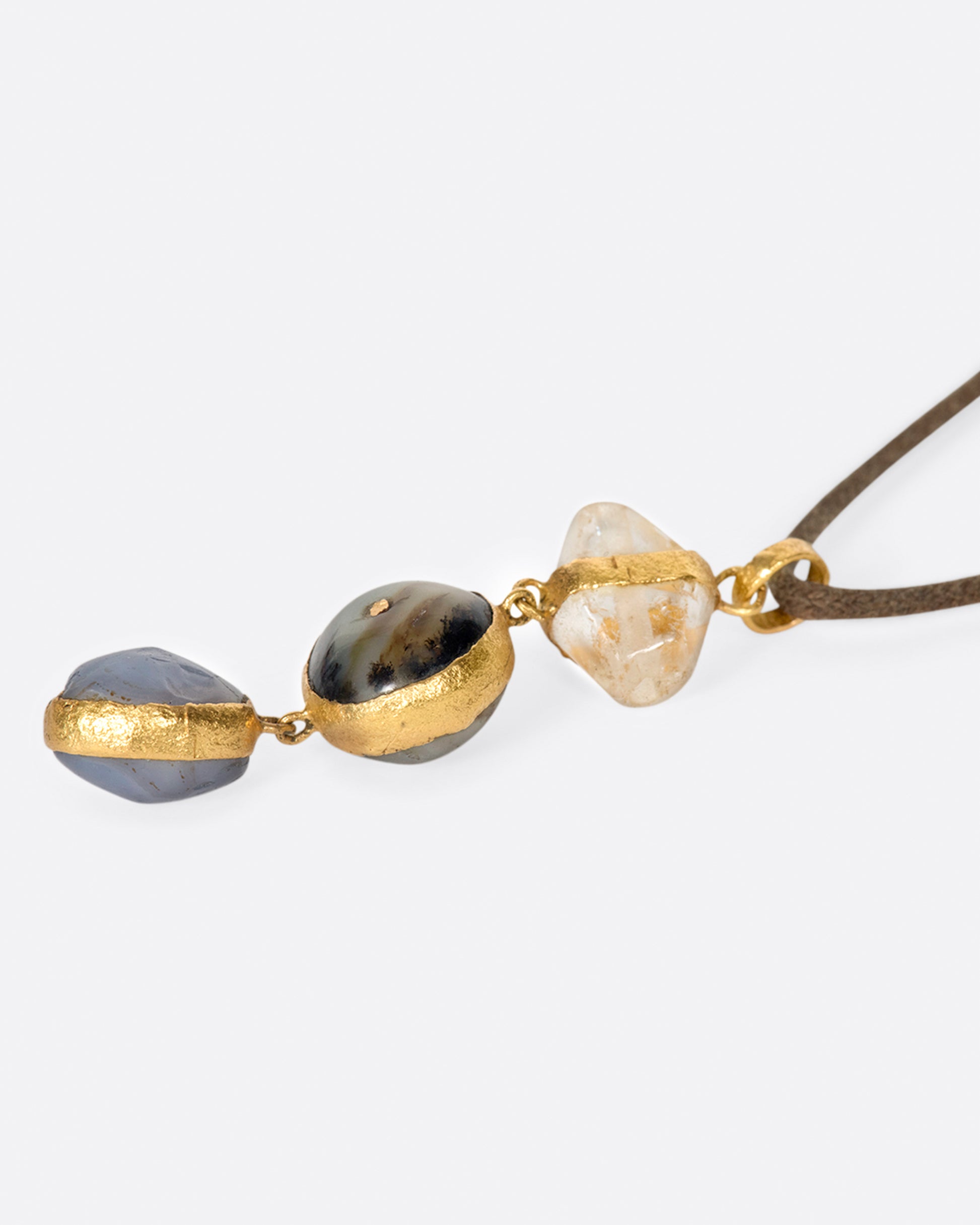 A high karat gold pendant with quartz, labradorite, and sapphire components.