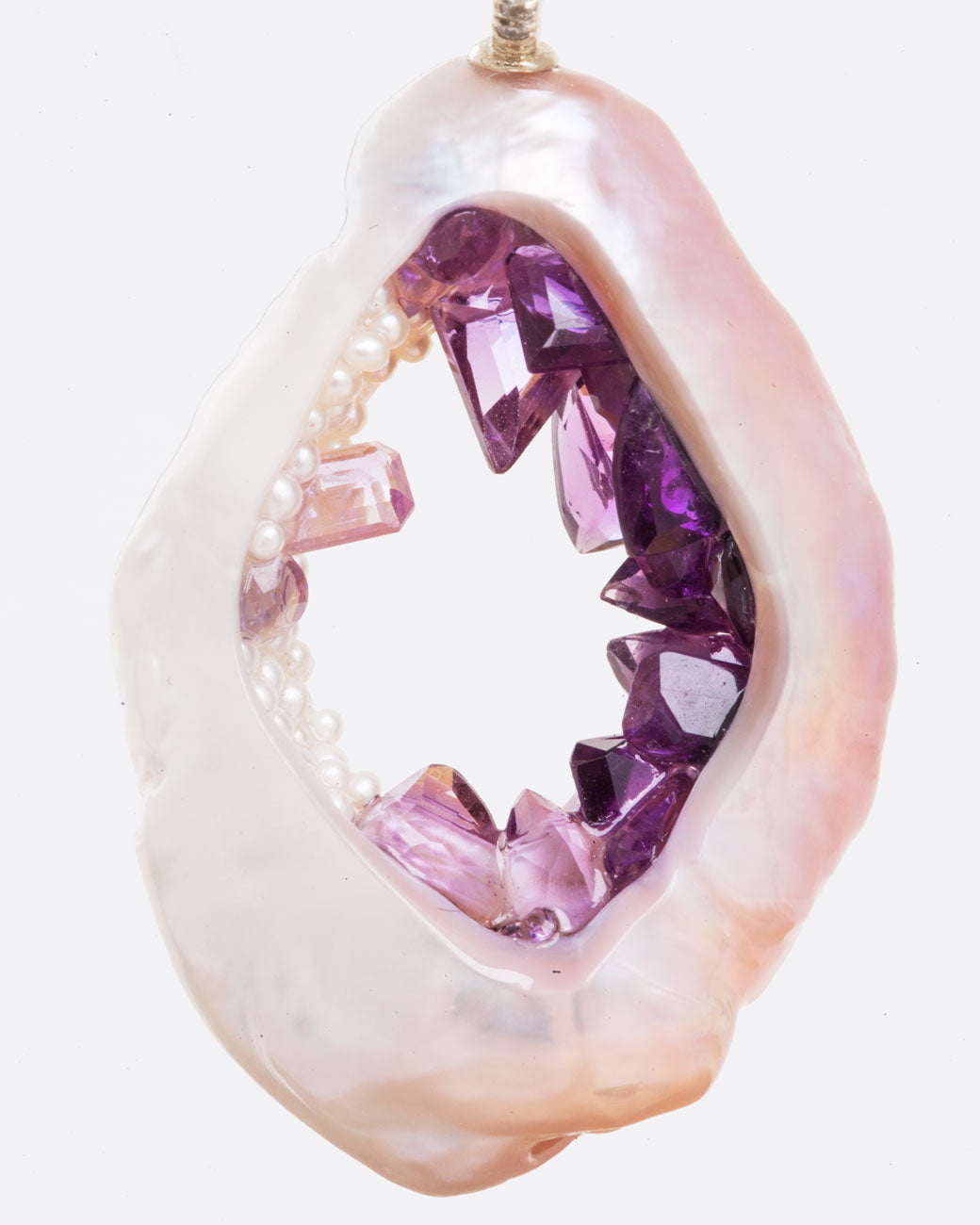 Very close up view of large souffle pearl with pink saturation gradient filled with pearls and amethysts following the color variation of the outer pearl