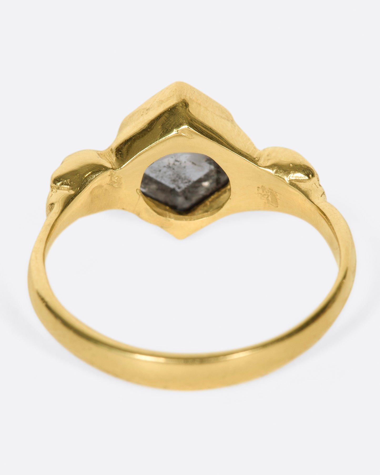 A bezel set, hexagonal, salt & pepper diamond ring with skulls on either side.