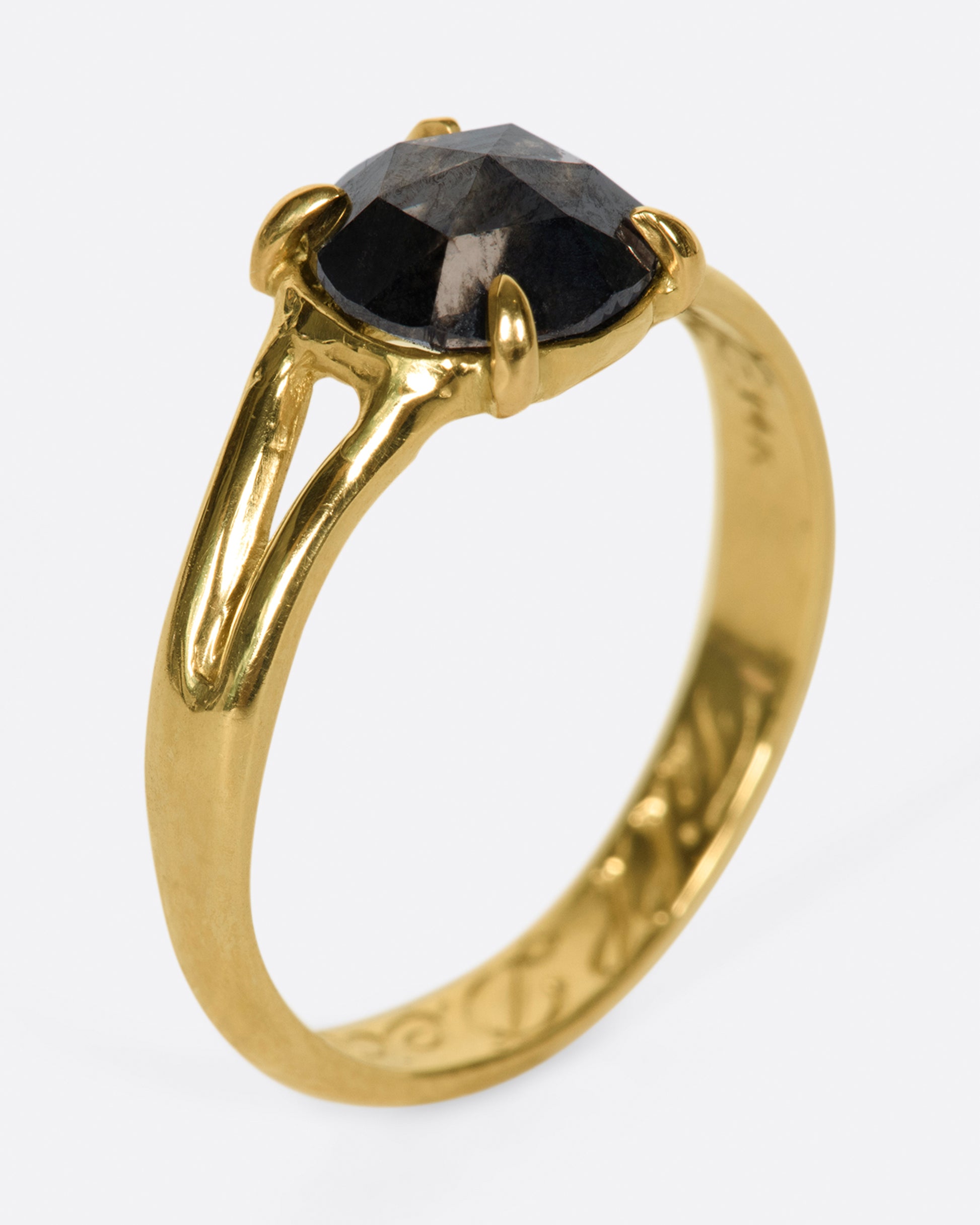 A split-shank gold ring with a prong set, rose cut, rustic diamond and "'till death" engraved on the inside.