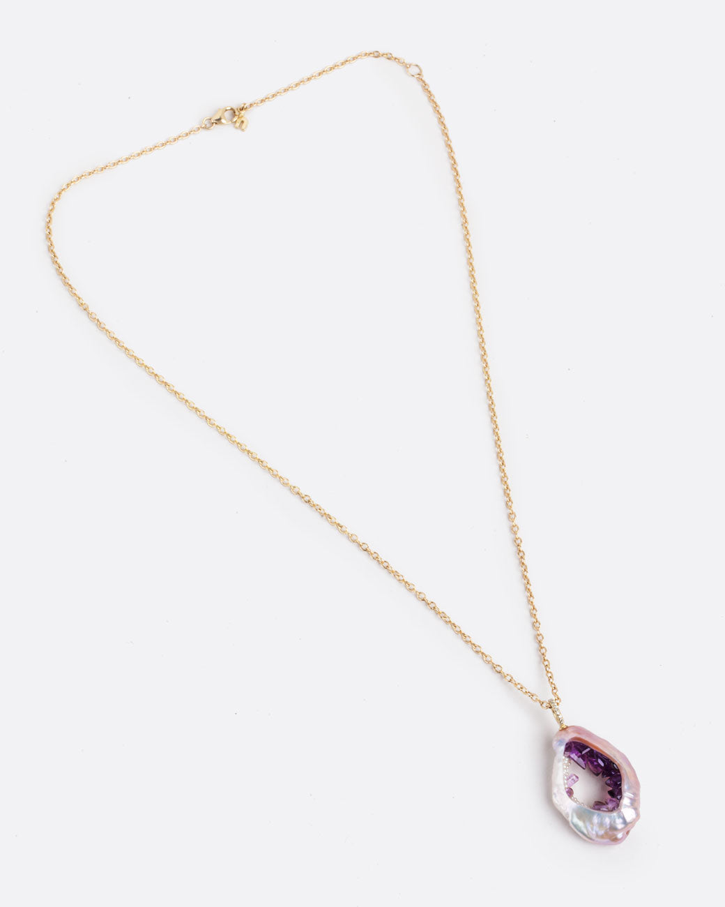 Layflat view of large souffle pearl with pink saturation gradient filled with pearls and amethysts following the color variation of the outer pearl, hanging from a yellow gold chain with pave diamond bail with clasp closed