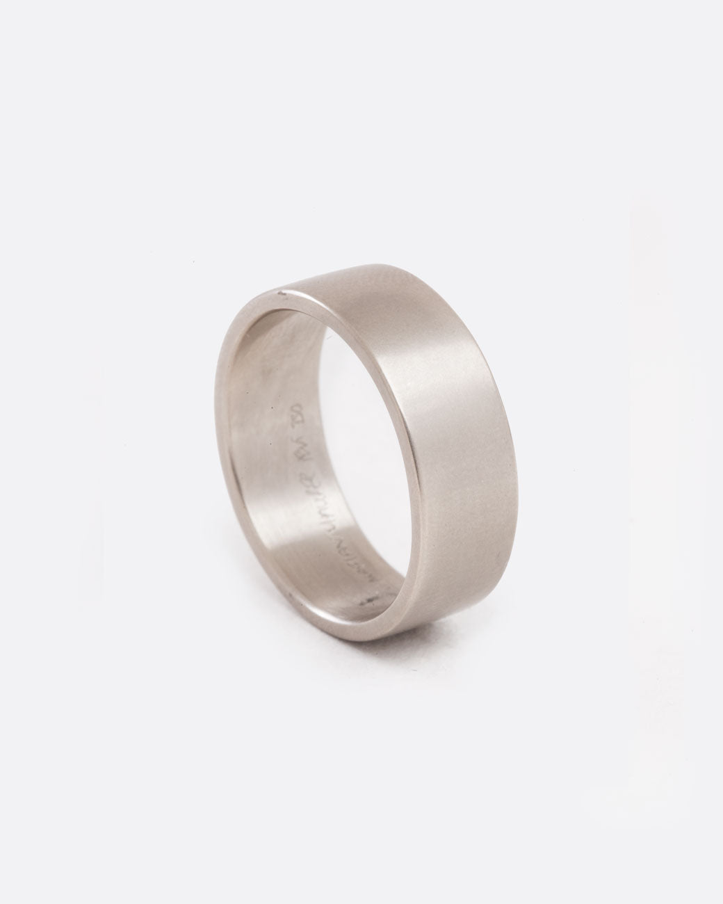 Slightly angled standing view of a simple, thick white gold band with matte finish