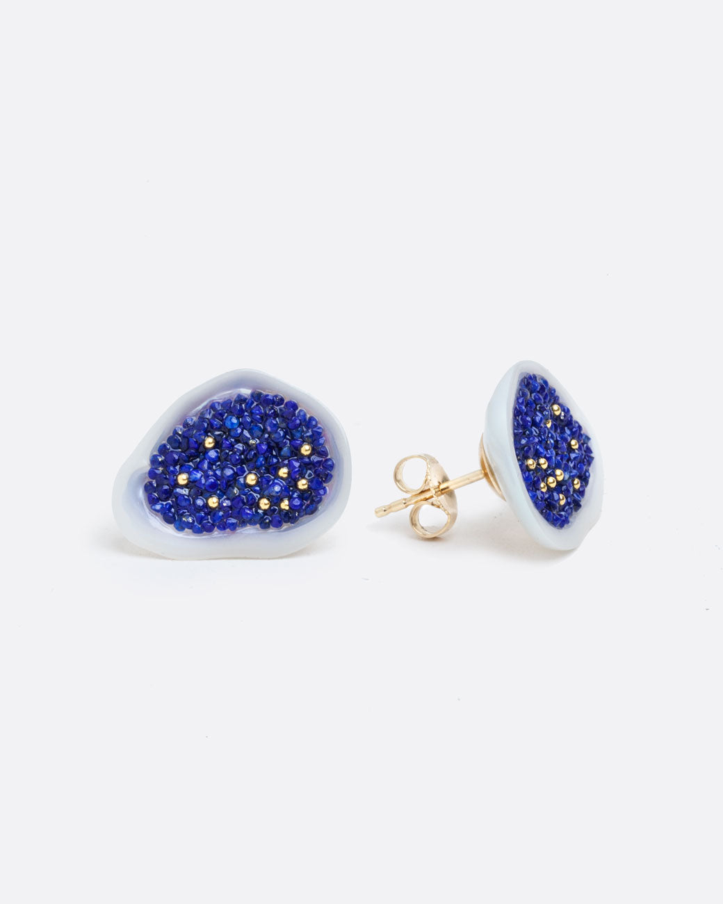 two earrings of a white souffle pearl that has been hollowed out and filled with small lapis pieces and small gold beads. with a yellow gold post back and yellow gold butterfly backing