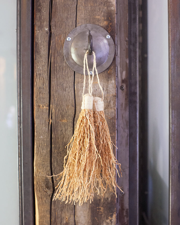 stylized image of vetiver tassle hanging from glass doorknob in a rustic room