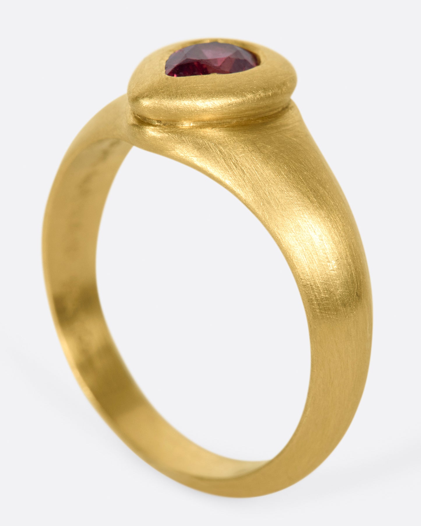 A one of a kind gold ring with a teardrop shaped orangey-pink spinel at its center.