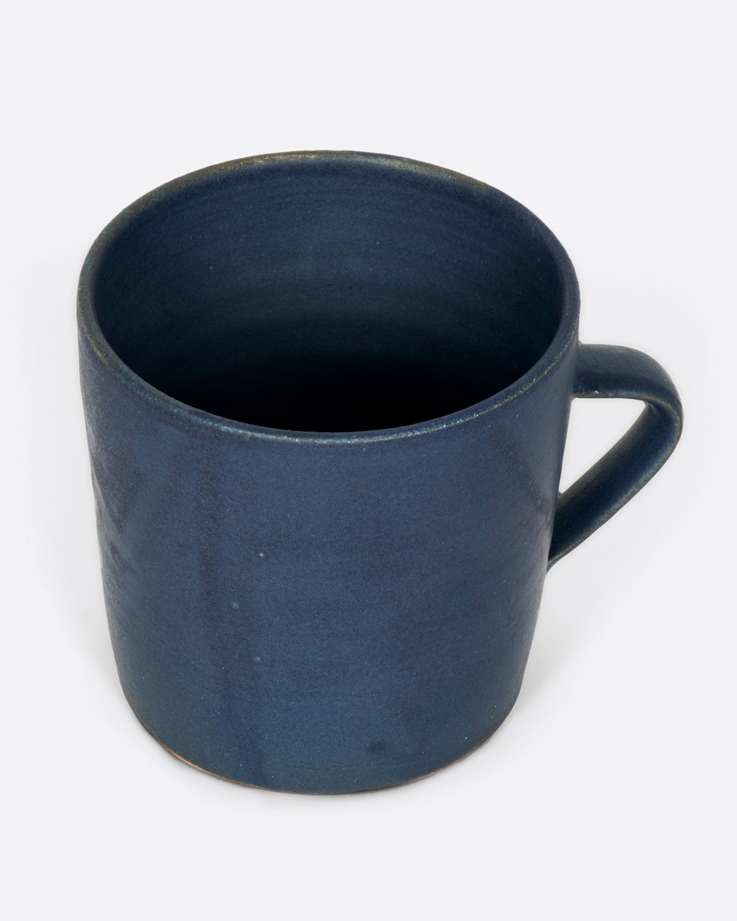 A hand thrown ceramic mug with a matte, deep blue glaze.