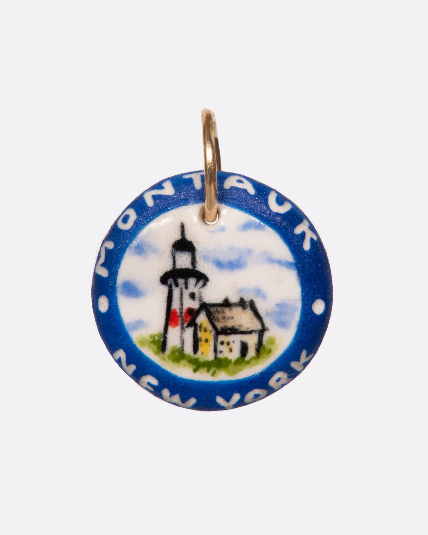 A round porcelain medallion, hand painted with the iconic Montauk lighthouse.