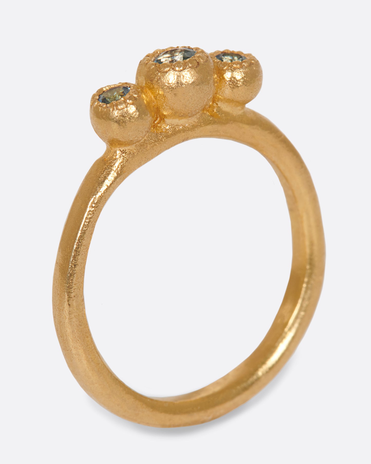 A handmade, high karat gold ring with three vibrant, bezel set aquamarines.