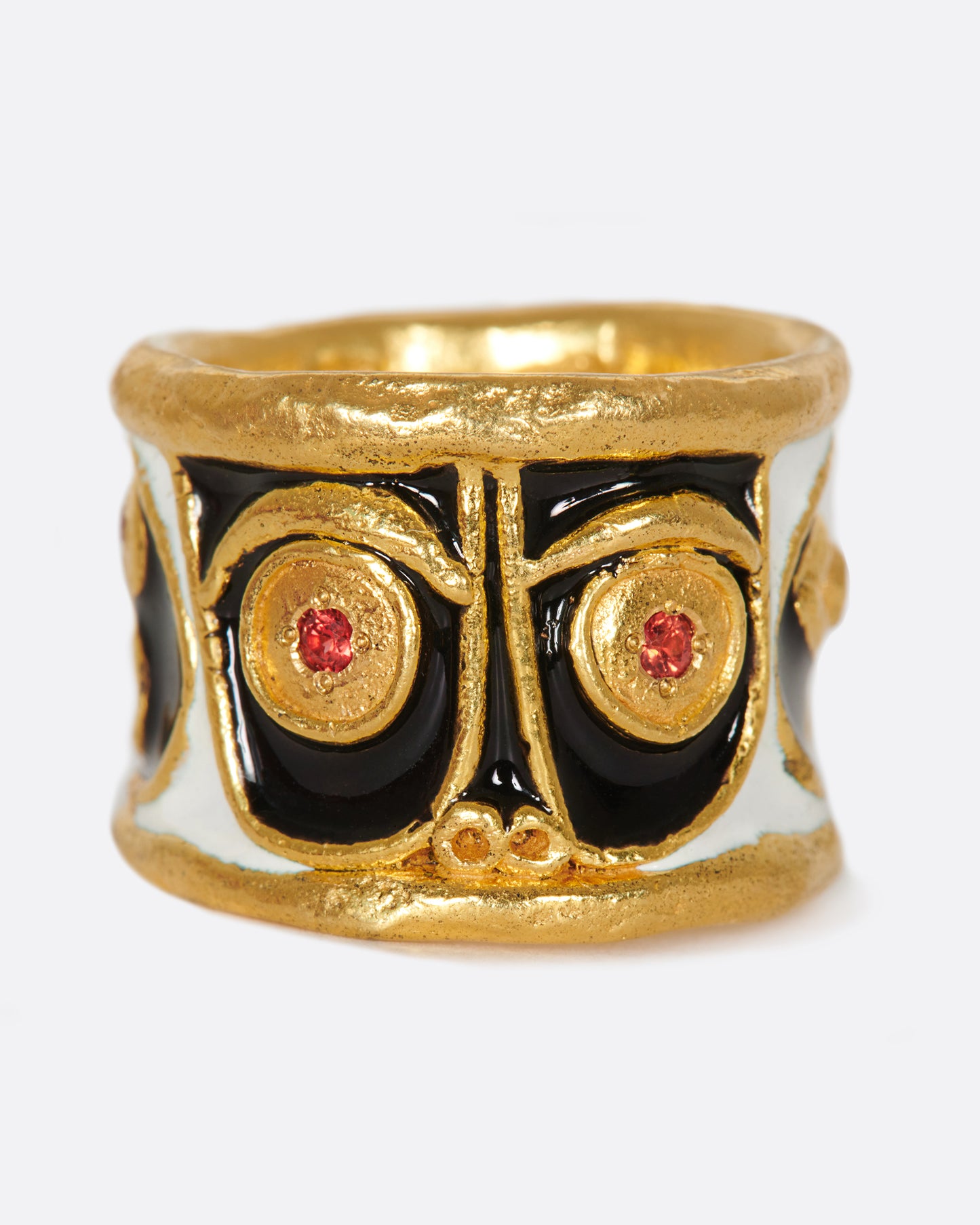 A handcrafted, high karat gold band with three faces illuminated by black and white enamel, and brightly colored stone eyes.
