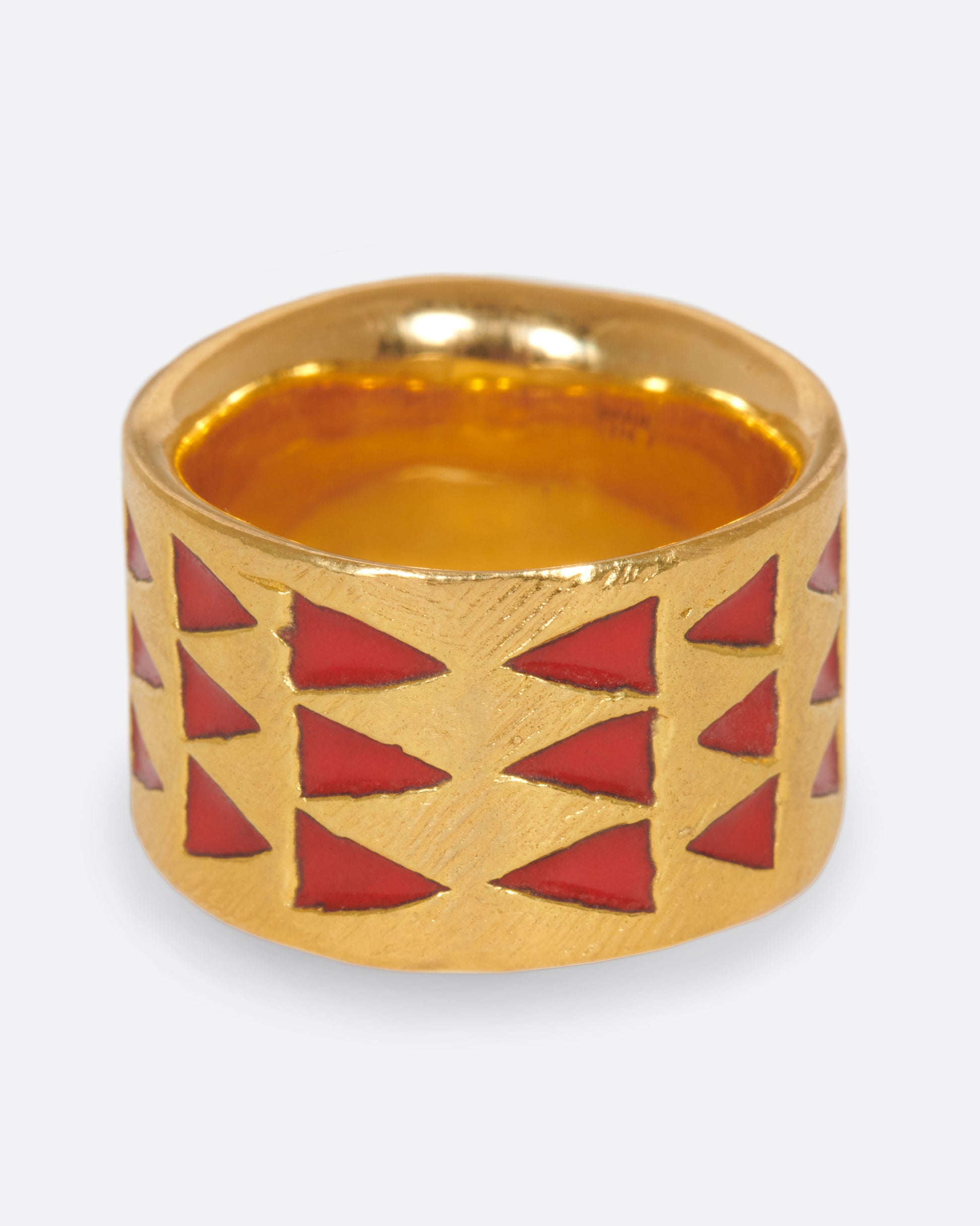 A handcrafted yellow gold band with red enamel triangles that meet at one center point.