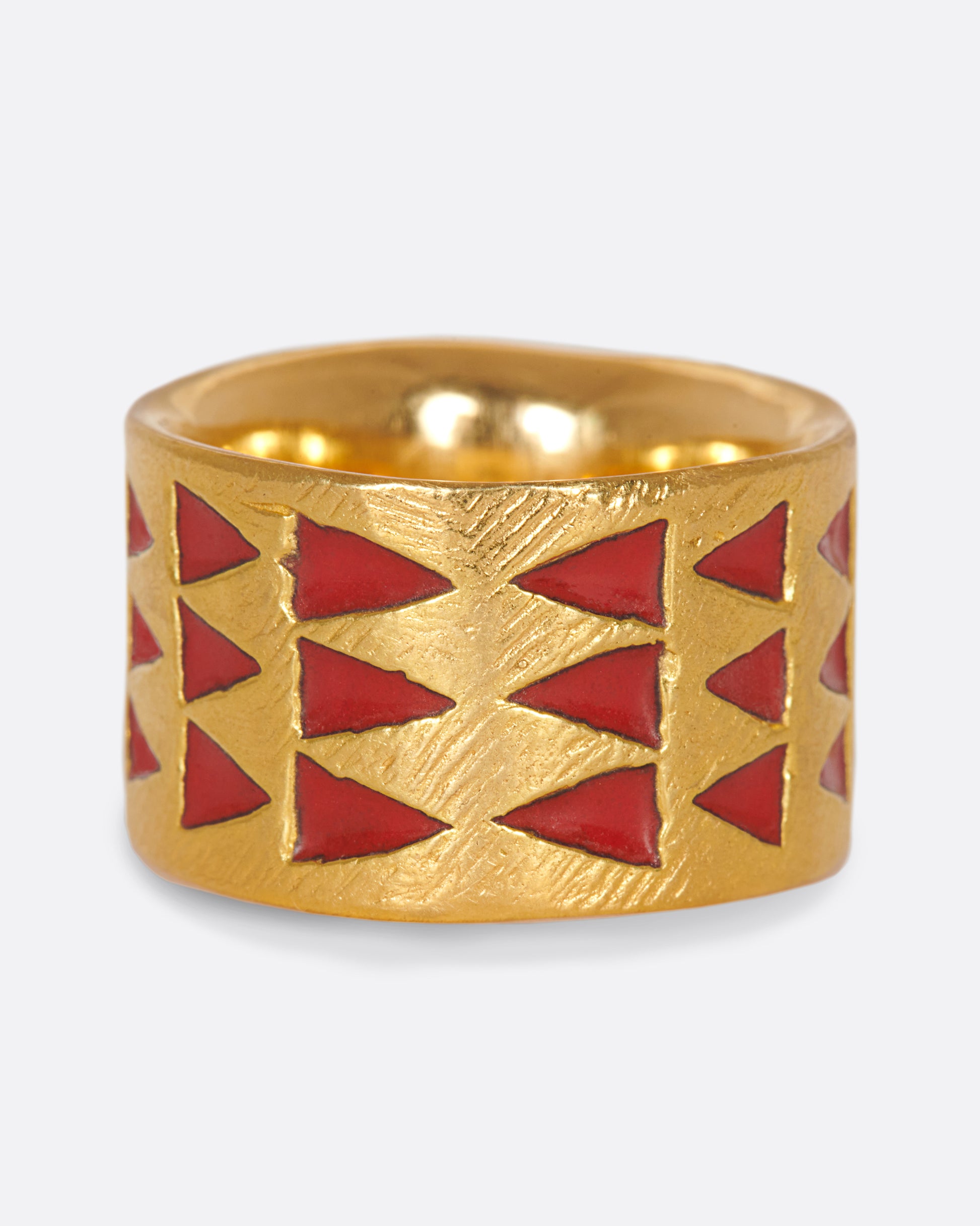 A handcrafted yellow gold band with red enamel triangles that meet at one center point.
