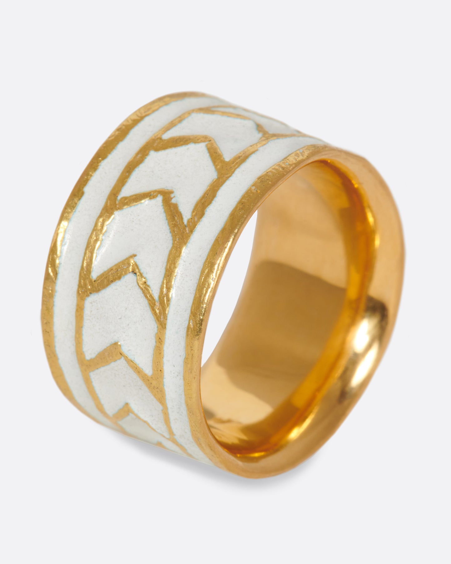 A handcrafted gold band with a path of consecutive arrows in white enamel.