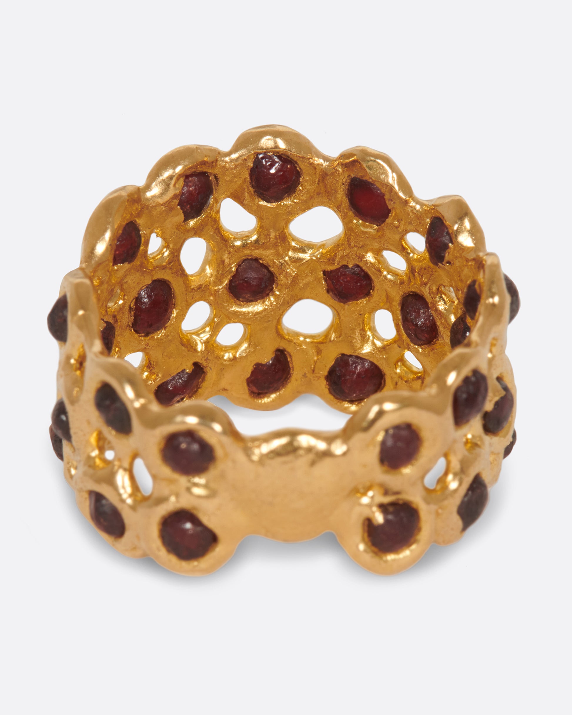 A ring made of a web of dark red garnet nuggets set in high karat gold bezels.