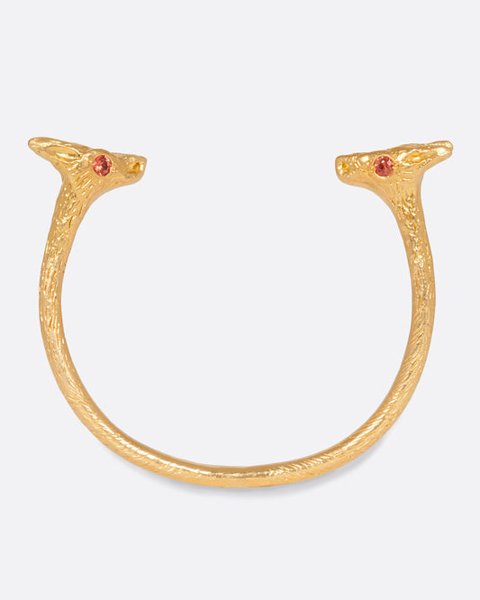 A solid 22k gold cuff bracelet with a fox at either end, accented by orange sapphire eyes.