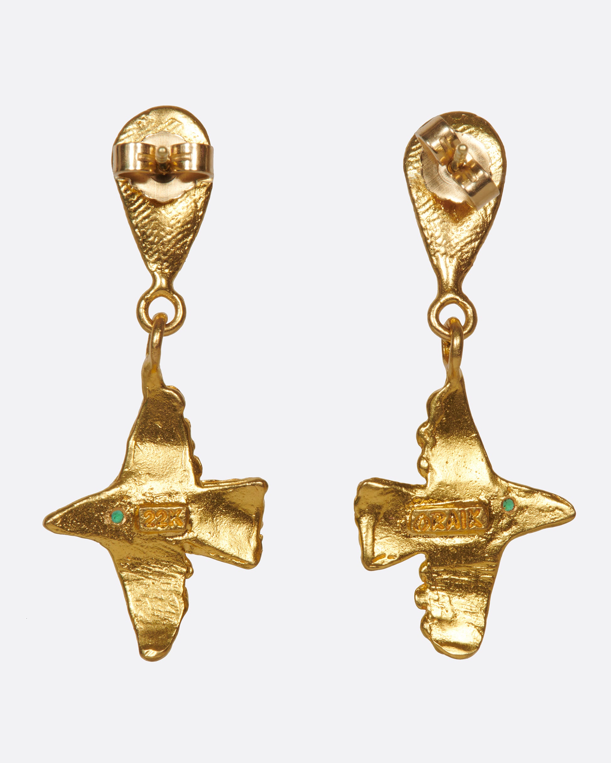 A pair of high karat gold drop earrings with flying birds and emerald eyes.