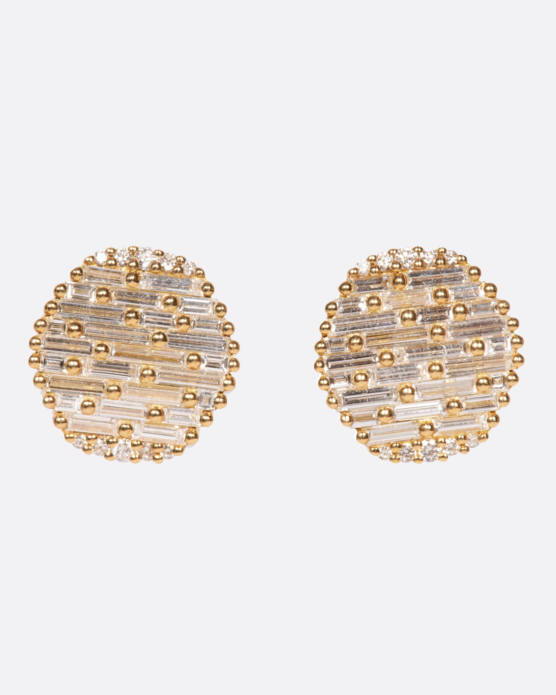 A pair of round, slightly concave stud earrings covered in baguette diamonds.