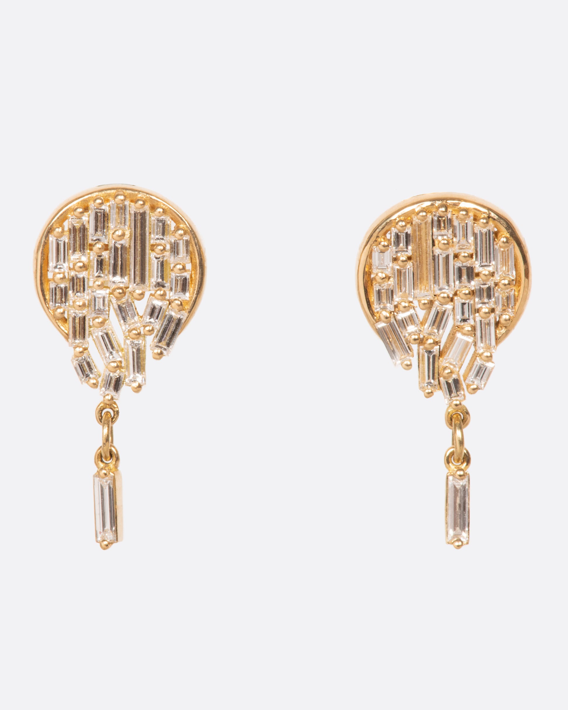 A pair of round stud earrings dripping with diamond baguettes.