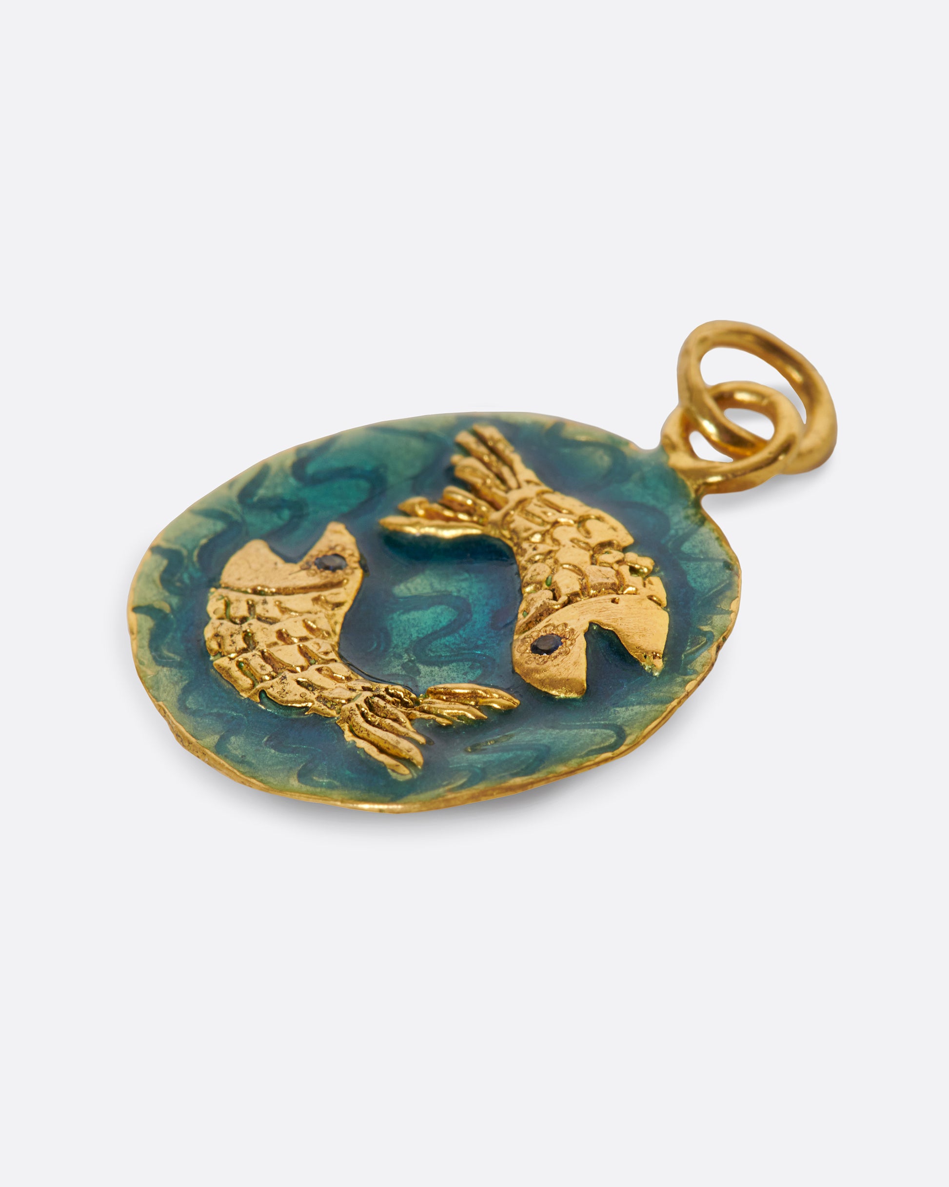 A round hand-sculpted pendant with the Pisces symbol, each fish with a blue sapphire eye.