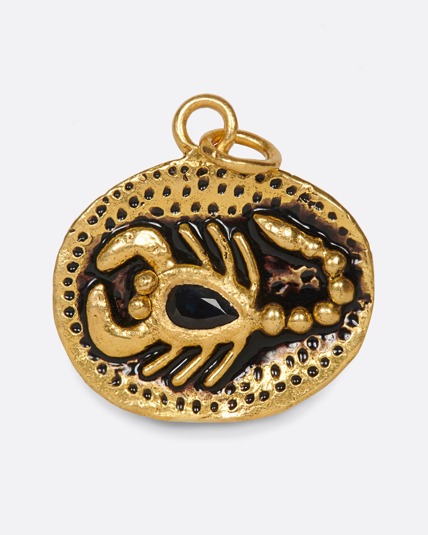 An oval gold pendant featuring a hand-sculpted scorpion with a pear shaped black sapphire body.