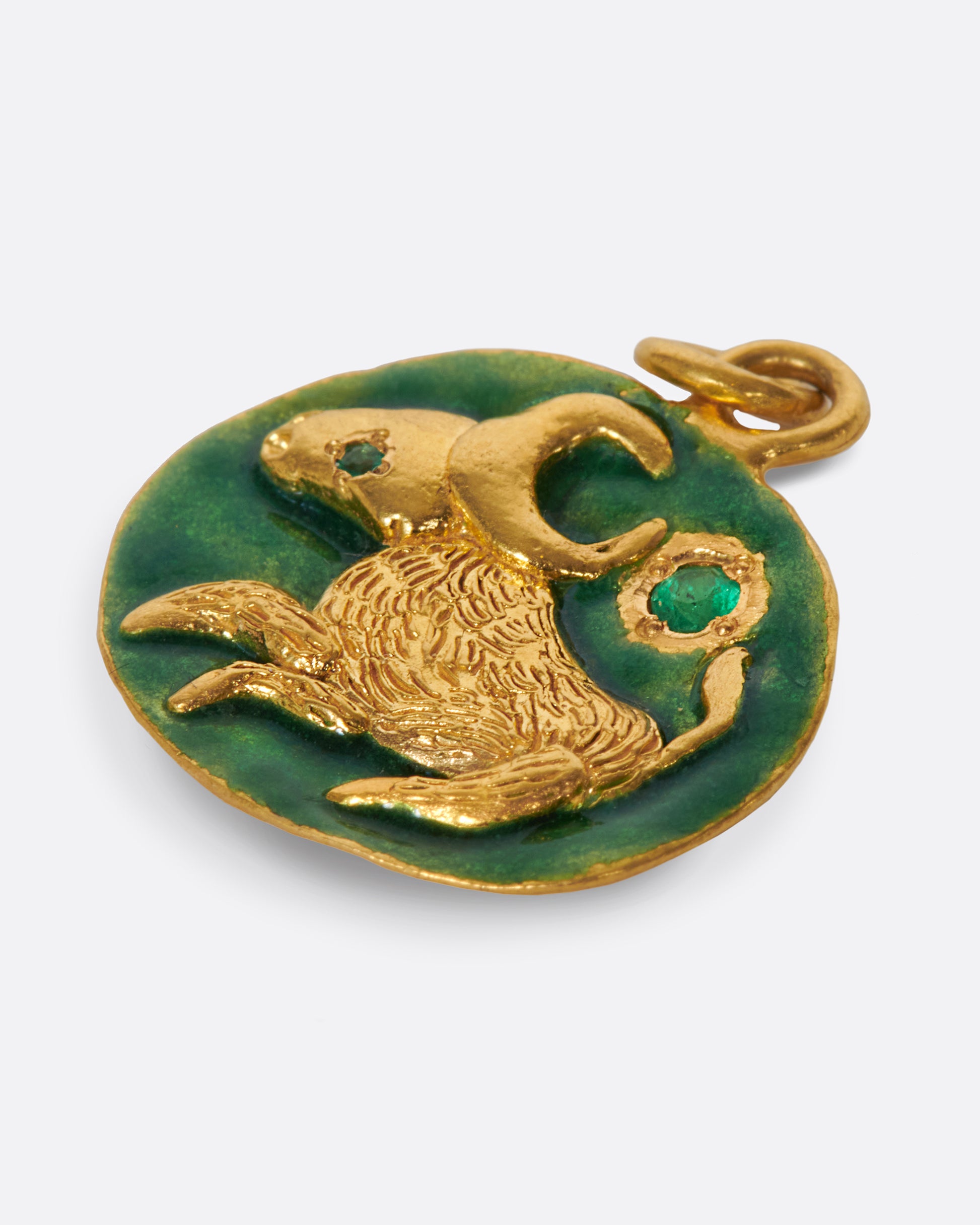 A slightly asymmetrical, circular pendant with a Taurus bull and emerald accents.