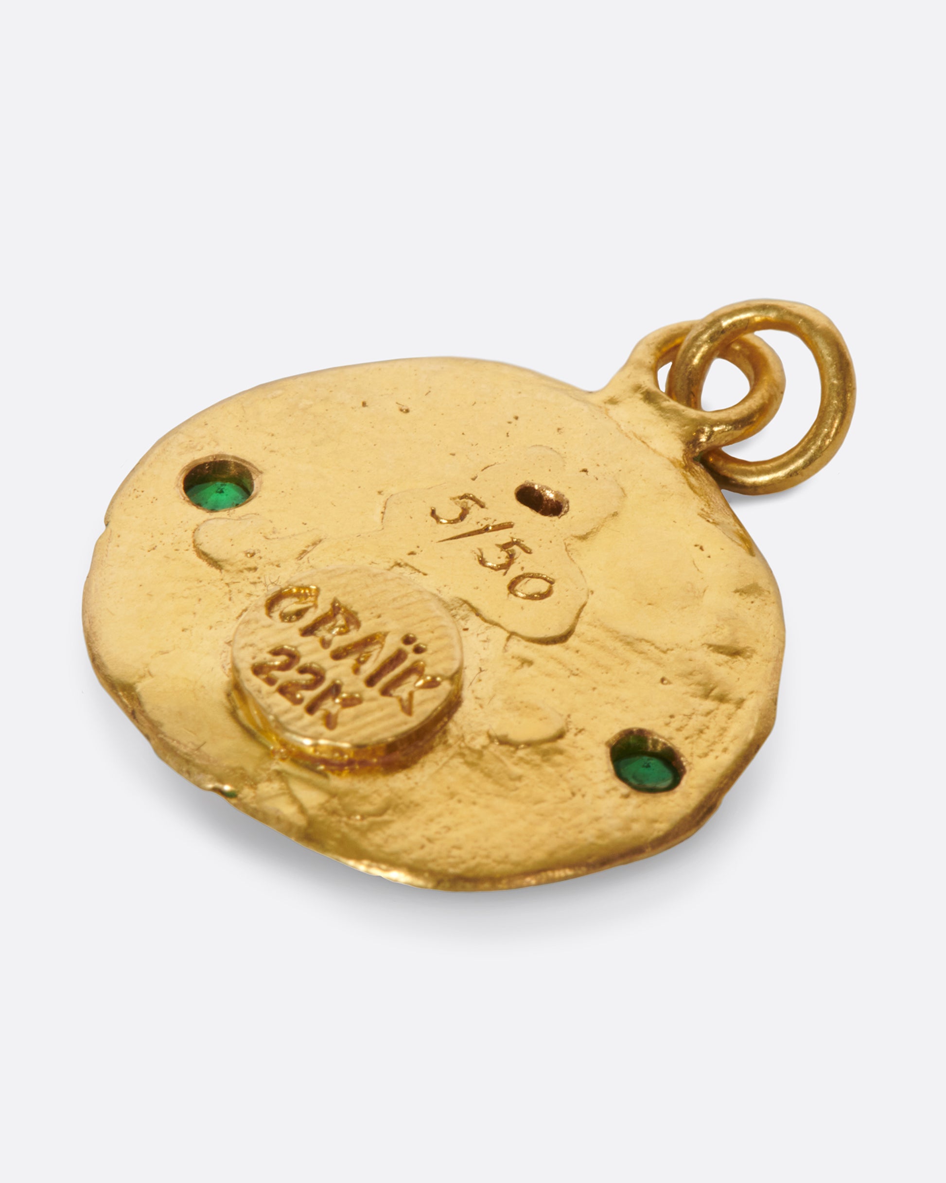 A round, high karat gold medallion pendant featuring a Virgo icon holding two tsavorite garnets.