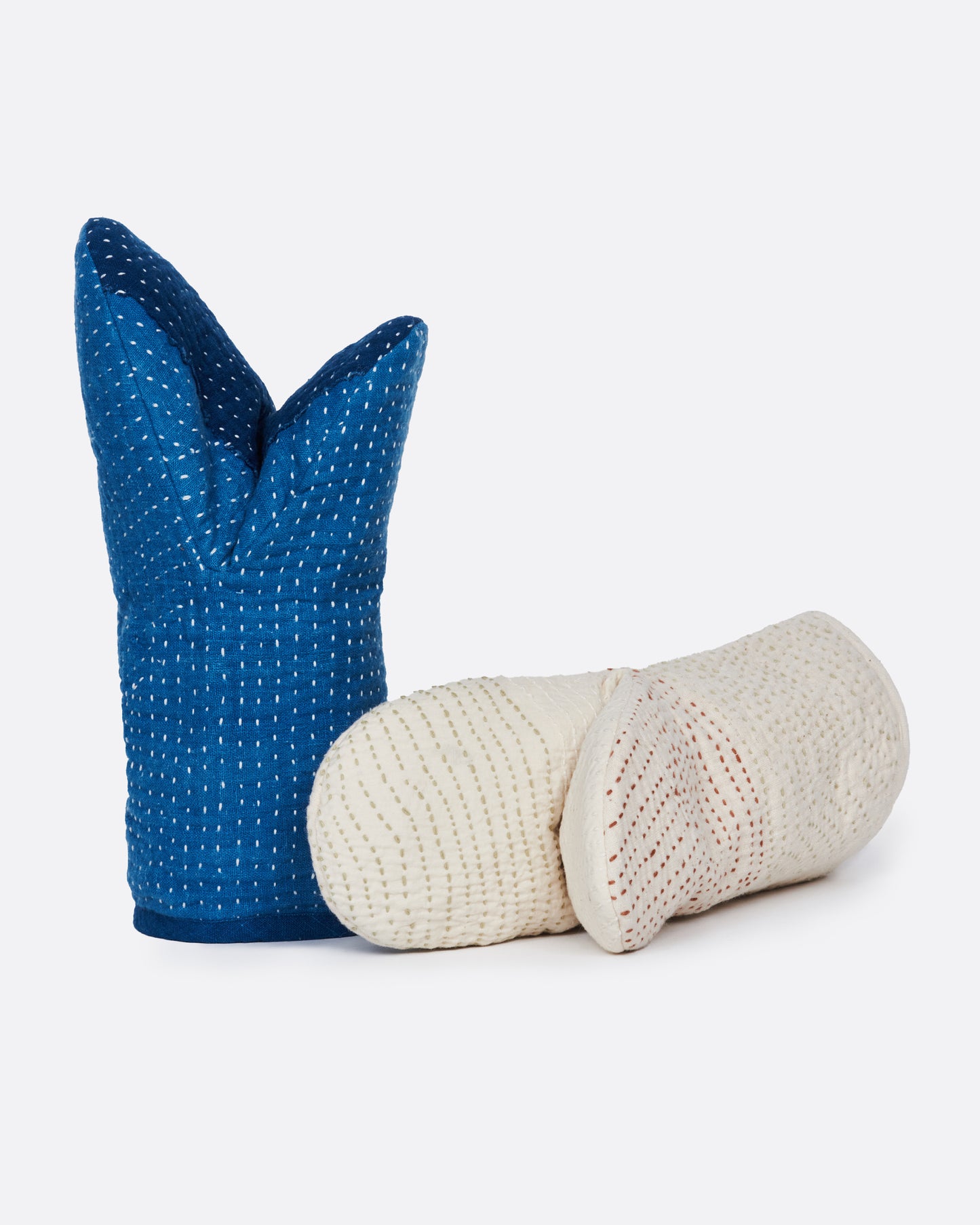 A pair of hand stitched oven mitts; one blue and one ivory.