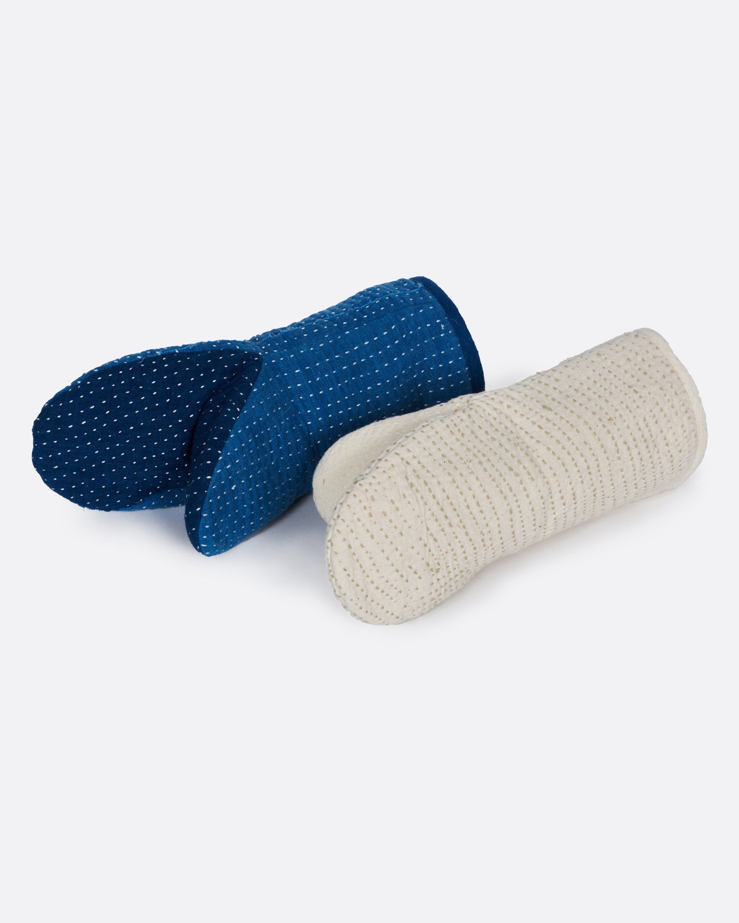 A pair of hand stitched oven mitts; one blue and one ivory.