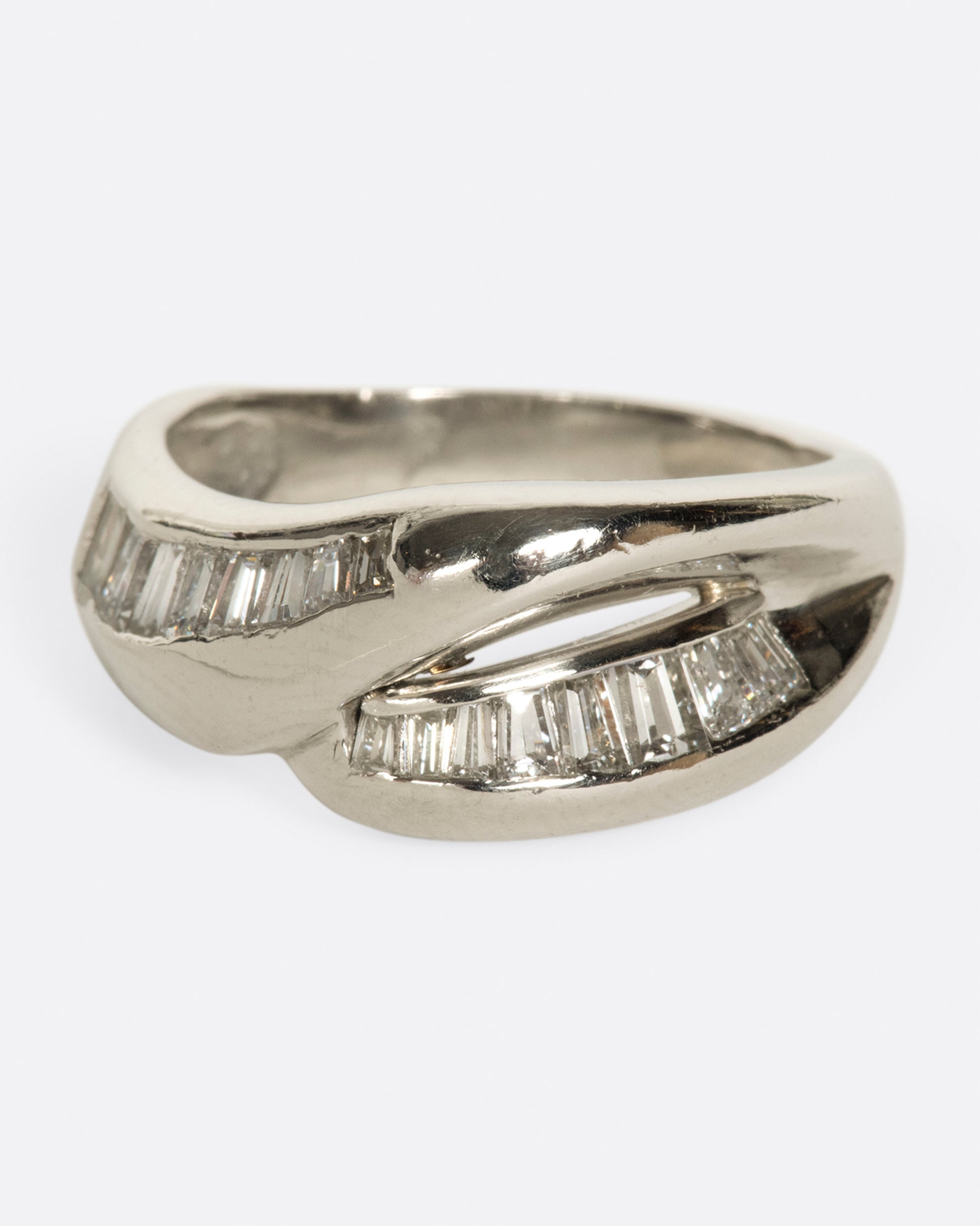 A platinum ring with two arches, lined with baguette diamonds.