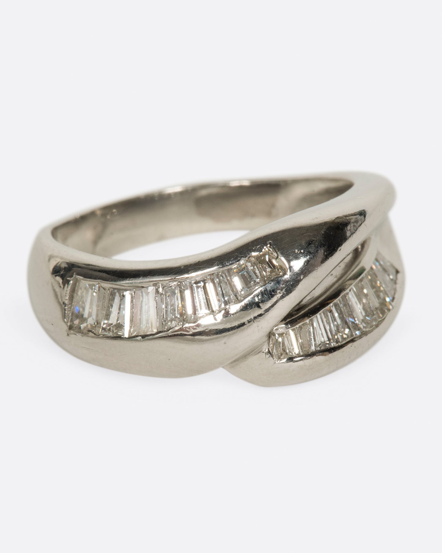 A platinum ring with two arches, lined with baguette diamonds.