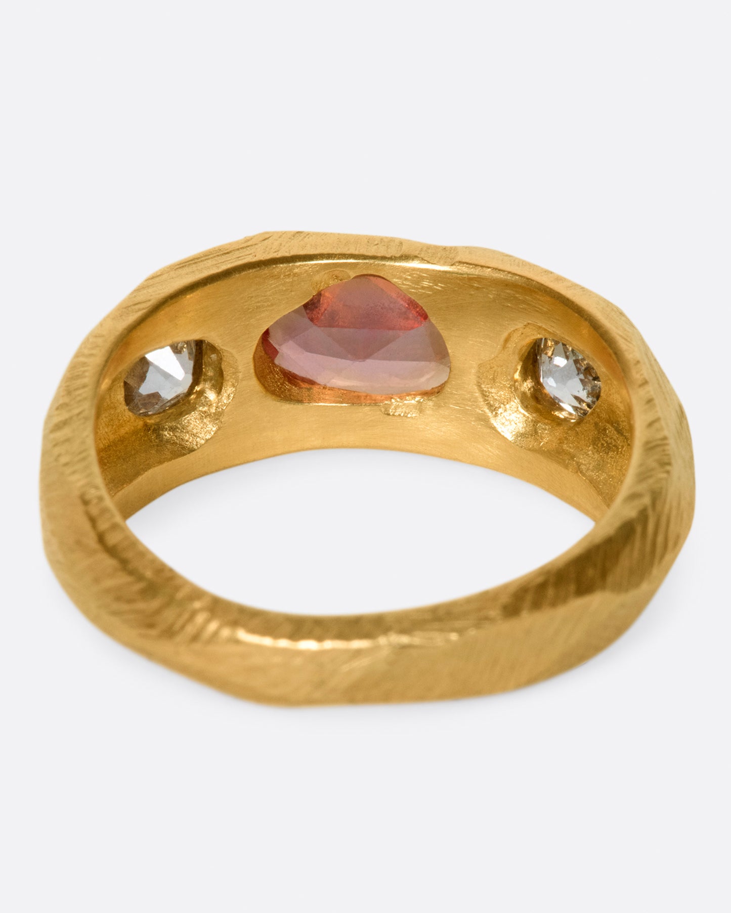 A one of a kind, hand carved ring with an oval rose cut orange sapphire and old mind cut white diamonds on either side.