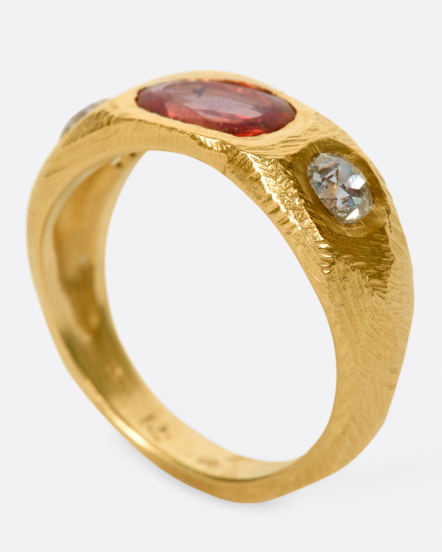 A one of a kind, hand carved ring with an oval rose cut orange sapphire and old mind cut white diamonds on either side.