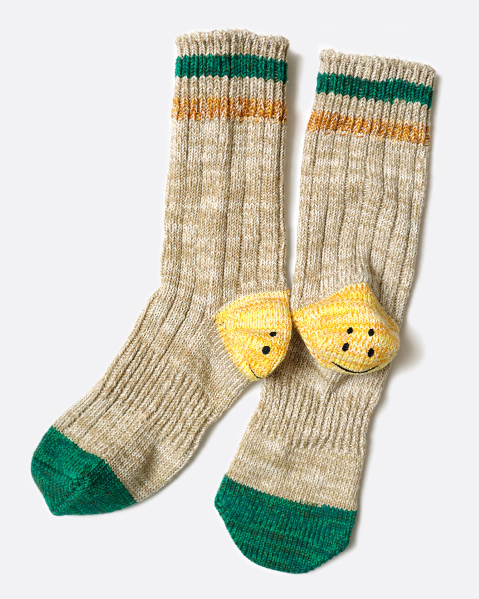 A pair of beige ribbed tube socks with green toe caps and yellow smiley heels, shown laying flat from the side.