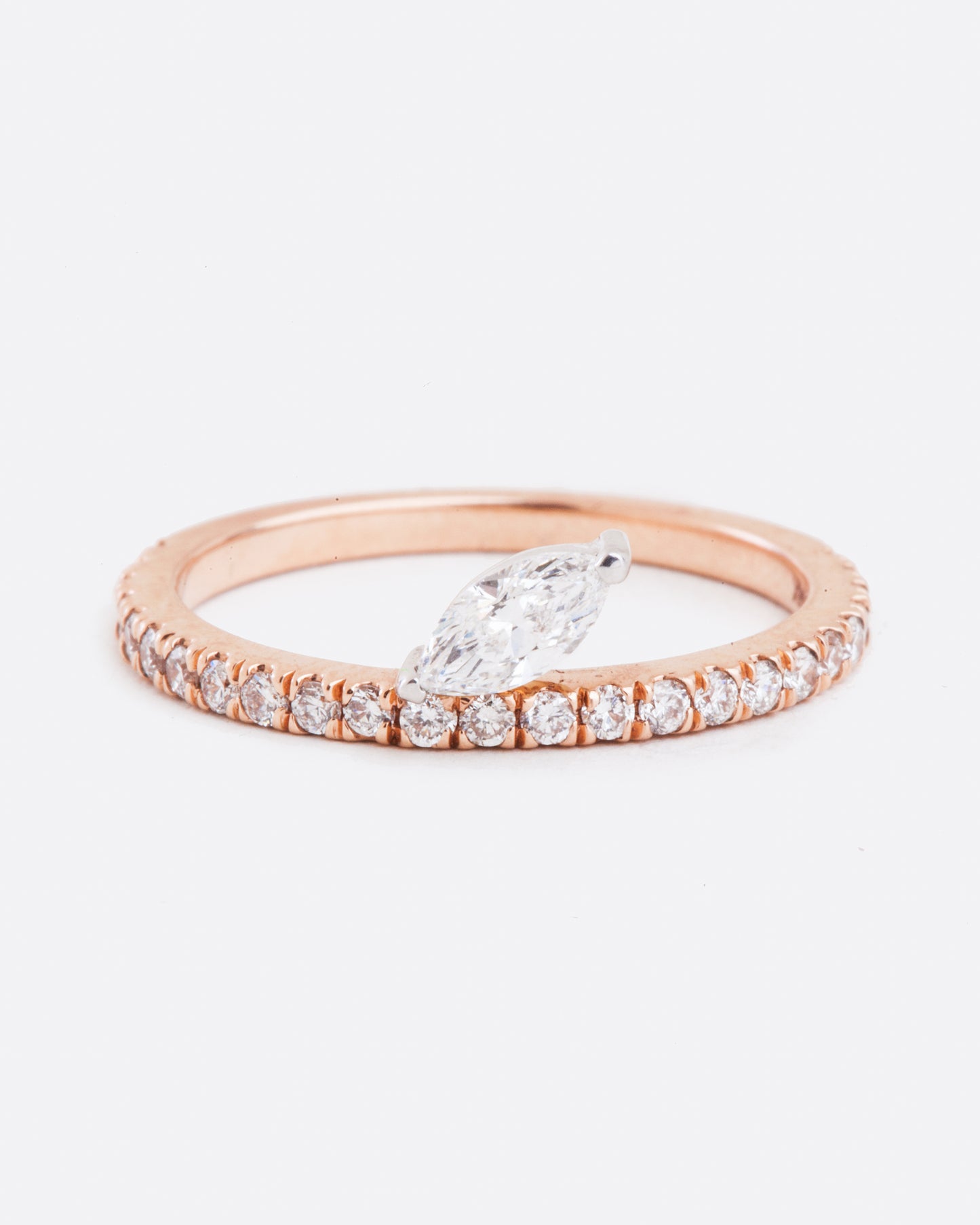 Front view of a marquise diamond sitting on a pave diamond rose gold band. The diamonds wrap 3/4 way around the ring.