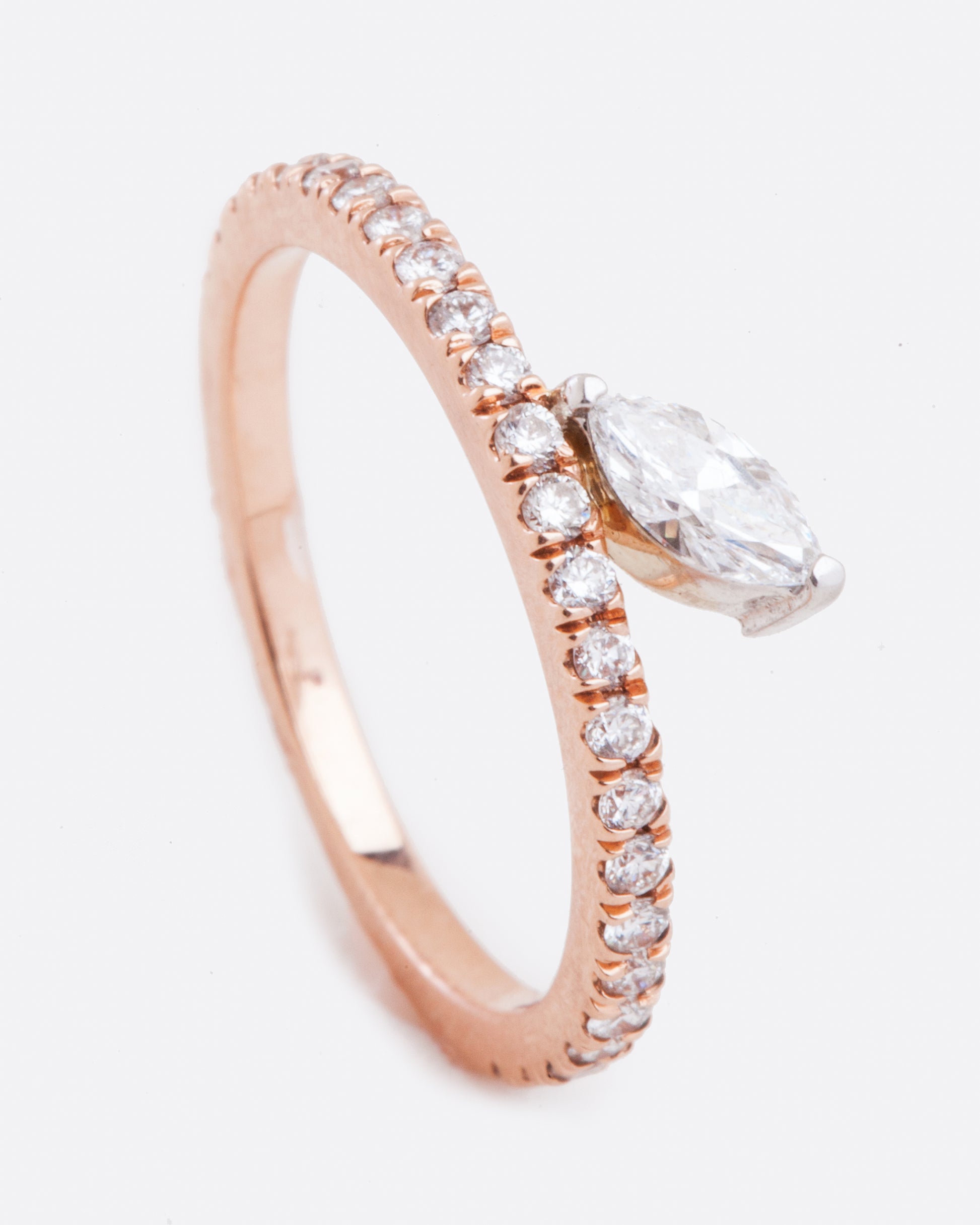 Standing view of a marquise diamond sitting on a pave diamond rose gold band. The diamonds wrap 3/4 way around the ring.