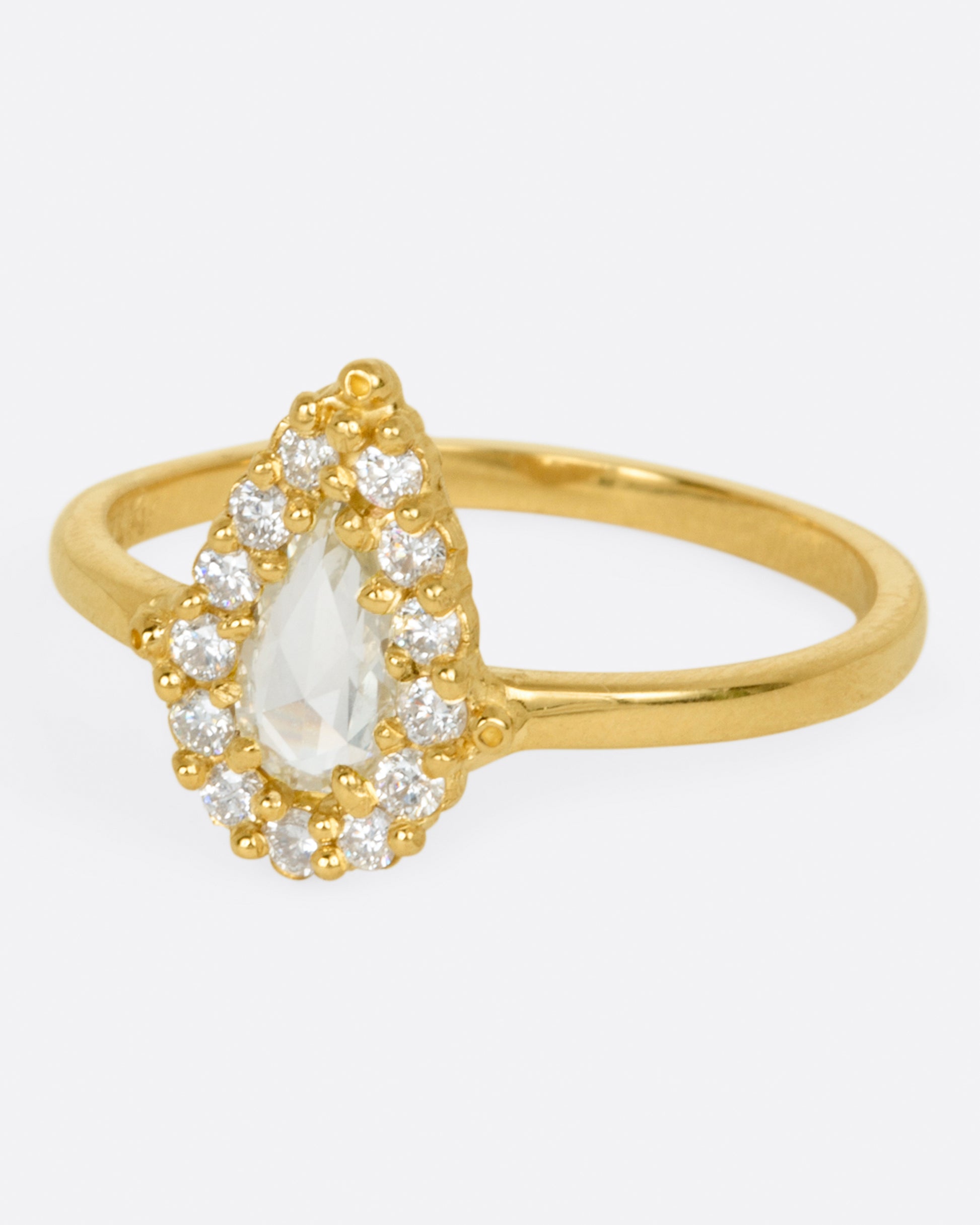 A light champagne, rose cut, pear shaped diamond ring with a round diamond halo.