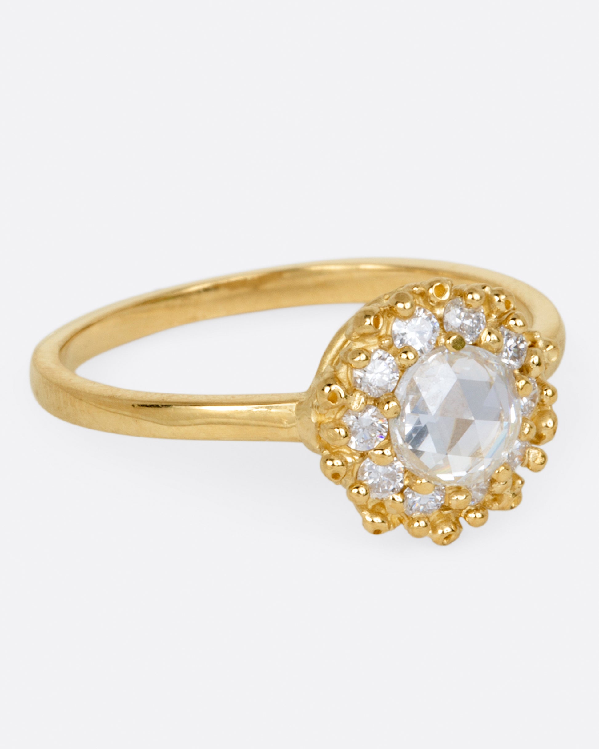 A rose cut round diamond ring with a halo of smaller round brilliant cut diamonds.